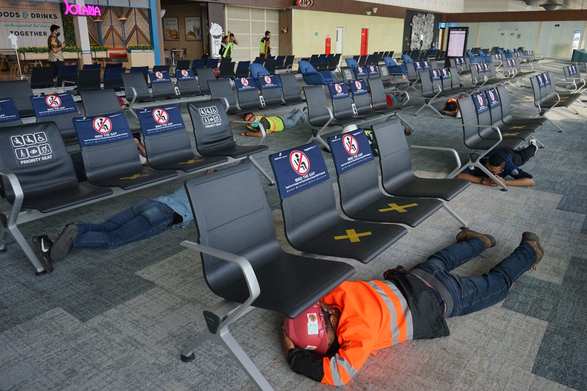 Petugas berlindung di bawah bangku saat latihan mitigasi tsunami di Yogyakarta International Airport (YIA), Kulon Progo, Selasa (6/10/2020).