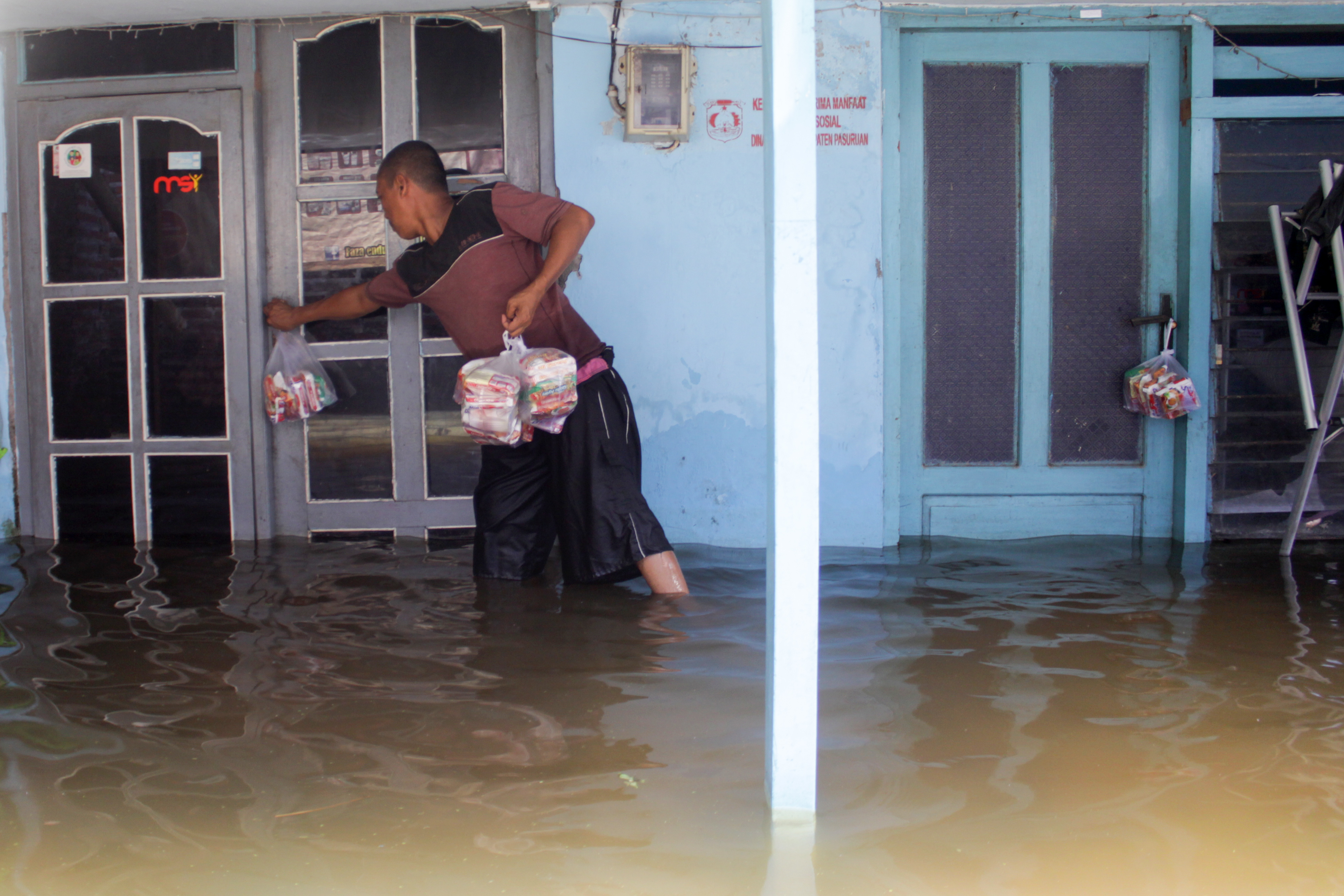 Relawan menyerahkan bantuan kepada warga korban banjir di desa Kedungringin, Beji, Pasuruan, Jawa Timur.