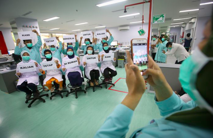 Petugas medis melakukan foto dengan memegang tulisan 