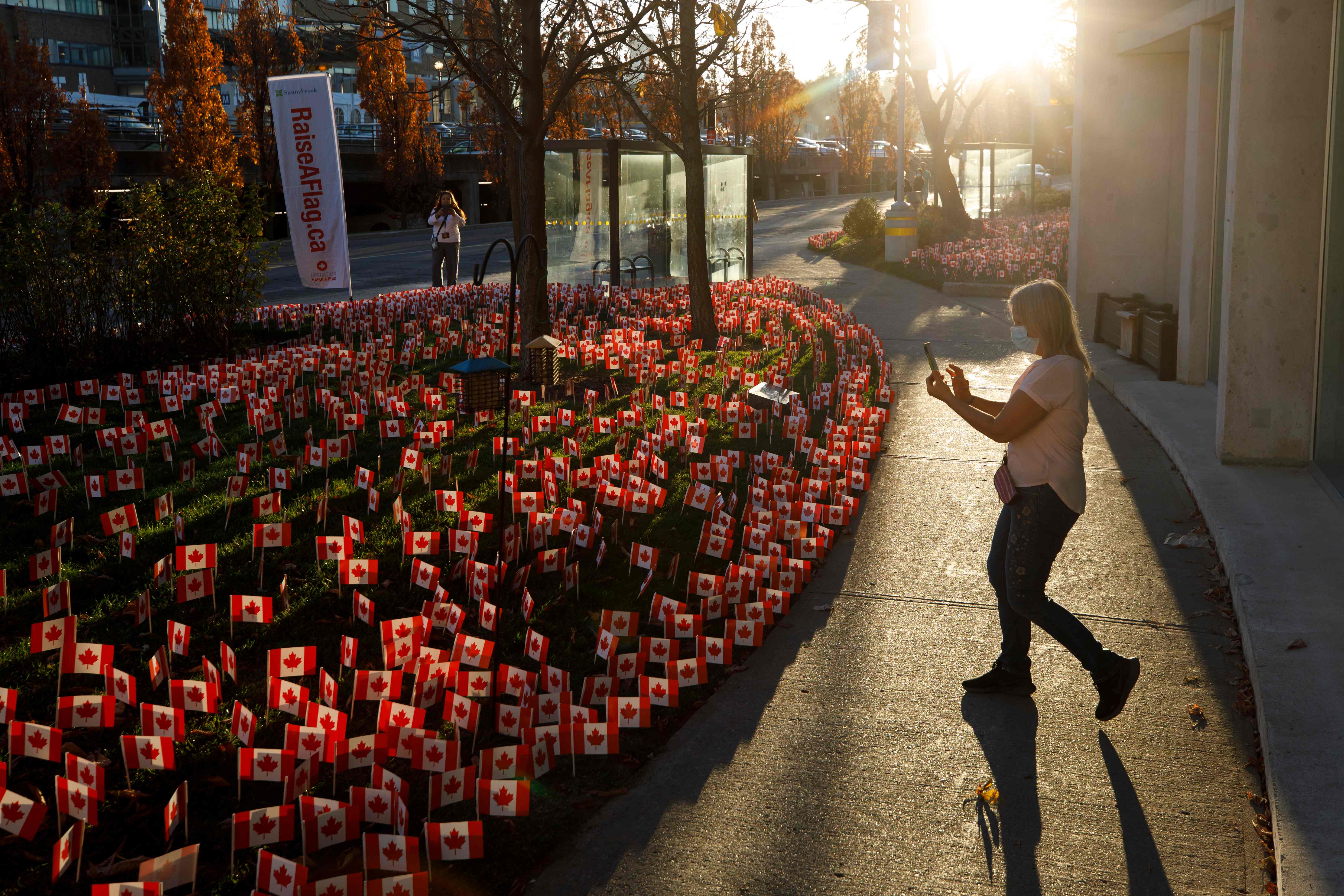 Seorang petugas kesehatan mengambil gambar miniatur bendera Kanada di luar Rumah Sakit Sunnybrook, Toronto, Kanada, Selasa (10/11/2020).