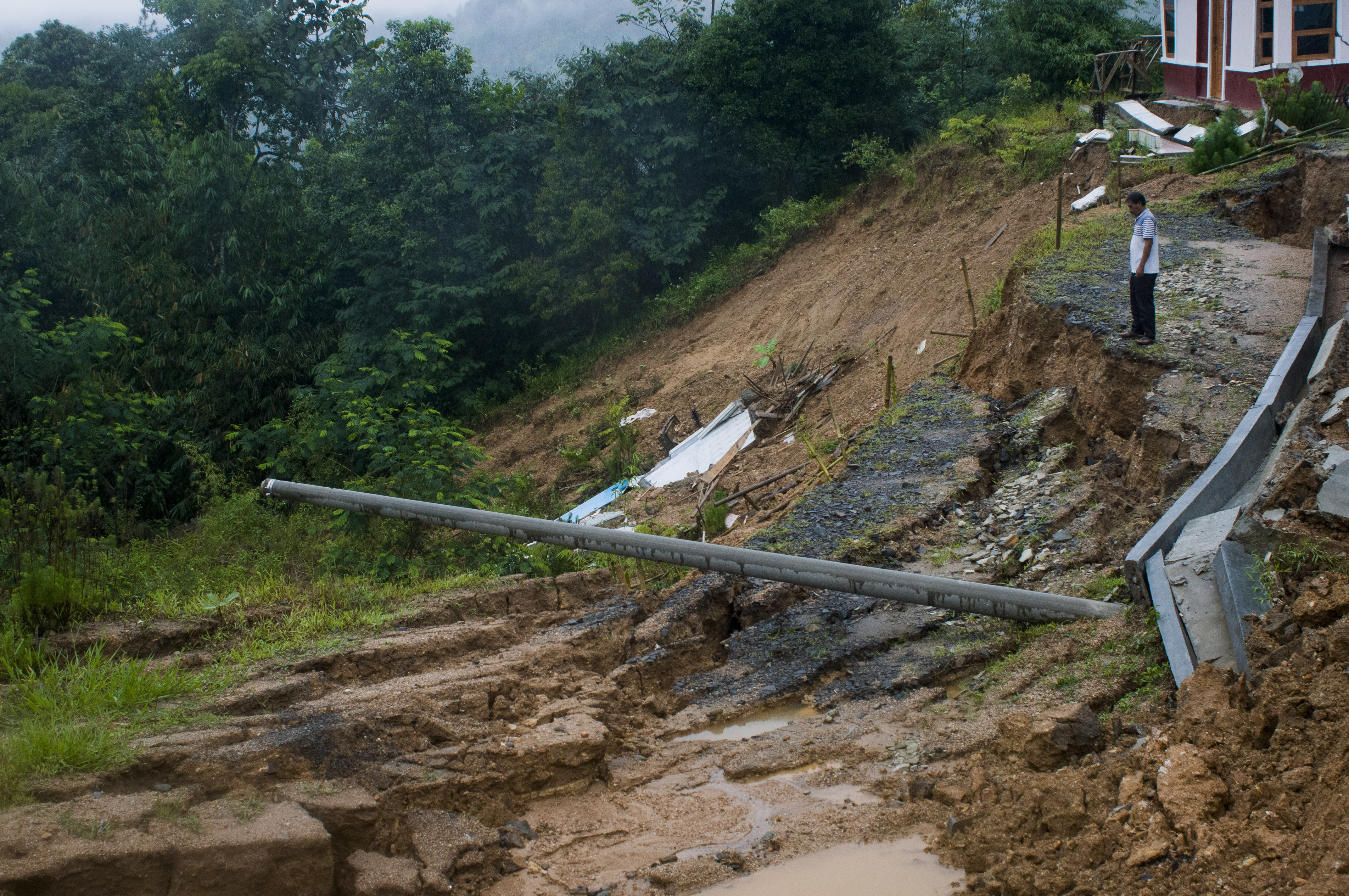 Penjaga sekolah melihat kondisi tanah longsor di sekitar gedung sekolah di SMAN 3 Cibeber, Lebak, Banten, Minggu (1/11/2020)