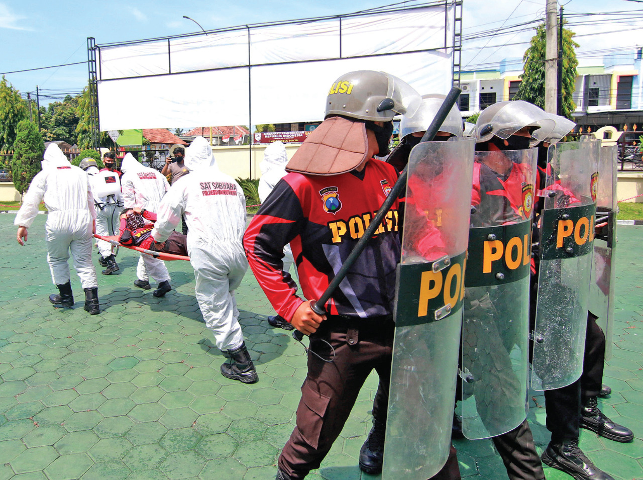 Anggota kepolisian melindungi petugas medis yang mengevakuasi petugas yang terluka dengan menggunakan alat pelindung diri (APD)