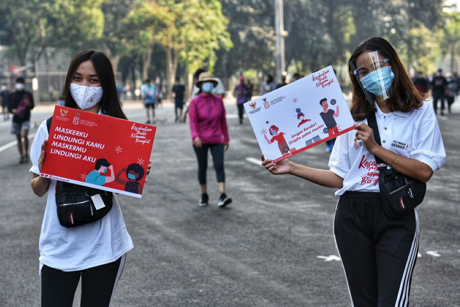 Dua remaja mengampanyekan gerakan memakai masker di Kompleks Gelora Bung Karno, Jakarta Pusat.