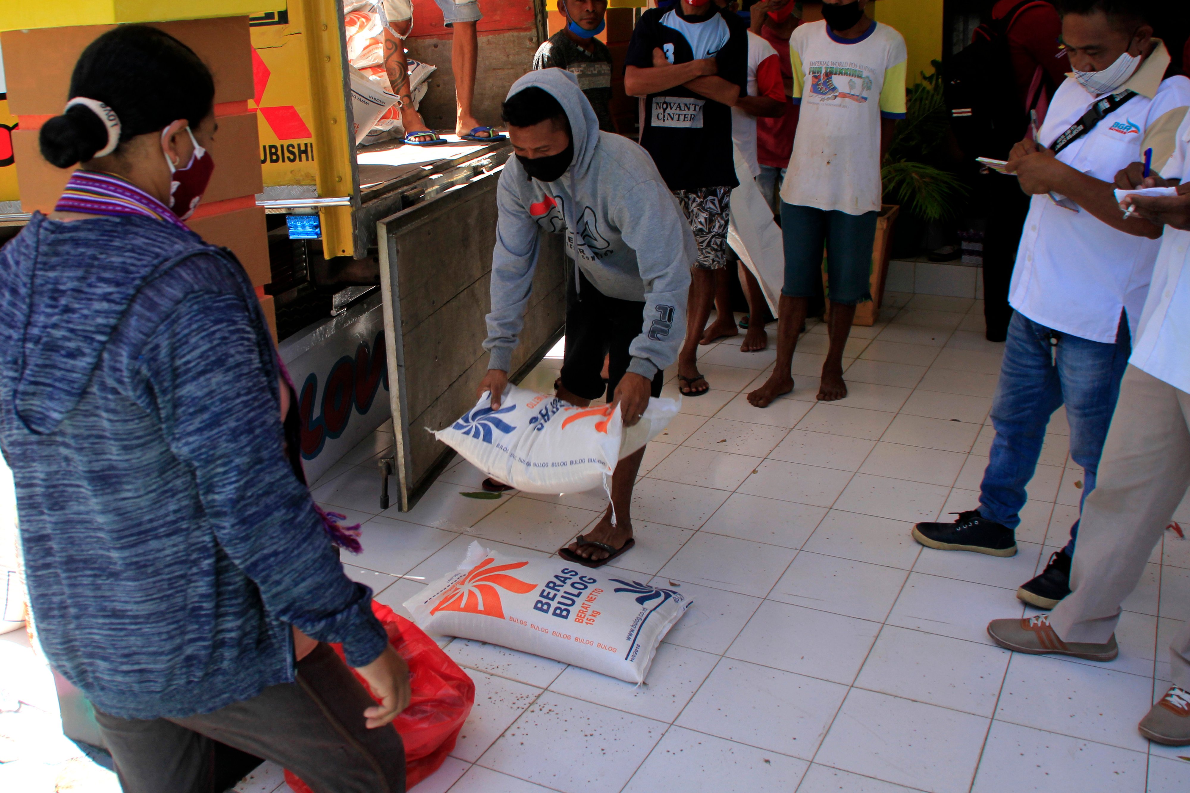 Petugas membagikan beras program bansos di Kota Kupang, NTT, Rabu (16/9).