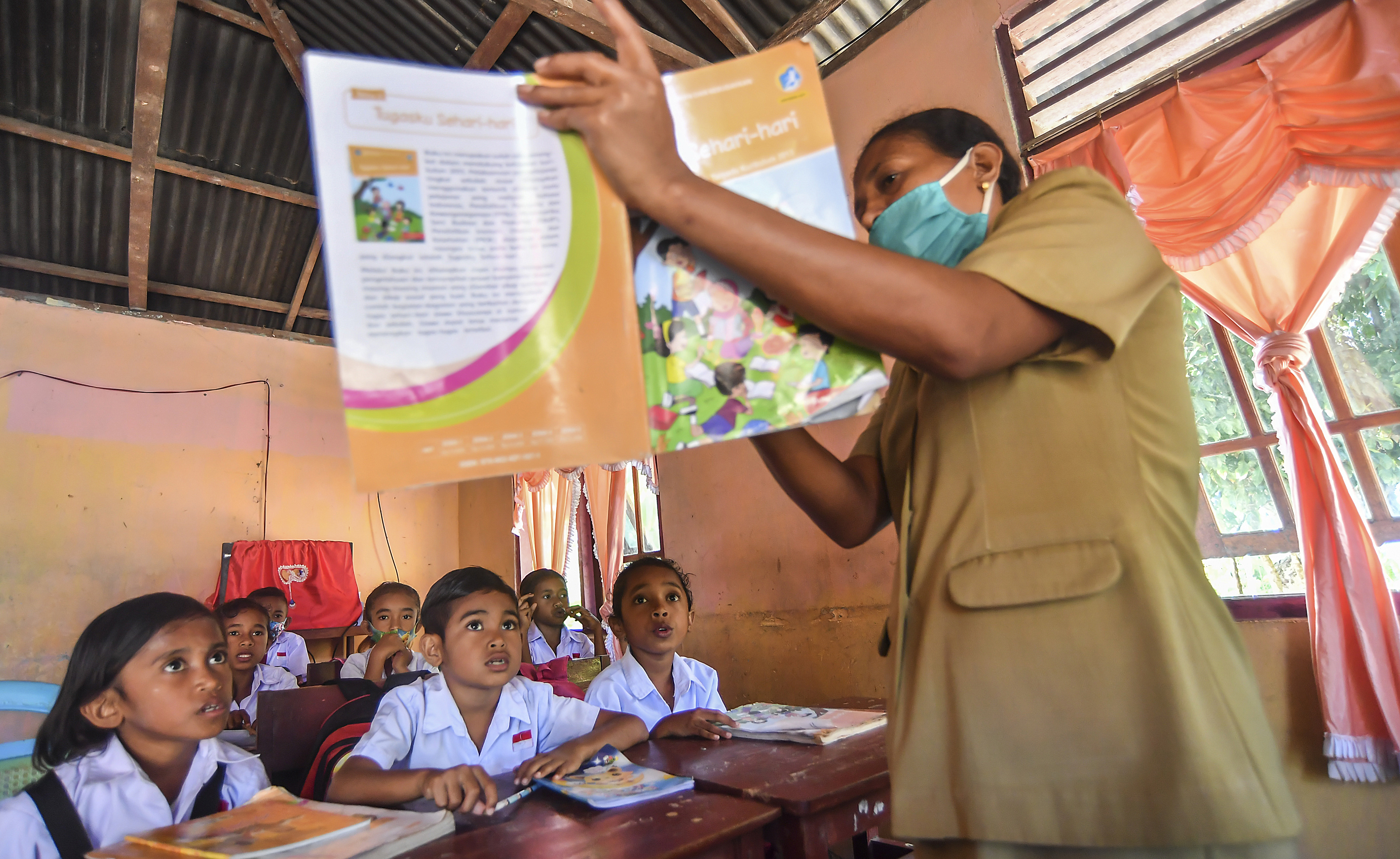 Seorang guru memberikan pelajaran saat di rumah siswa di Desa Nuruwe, Seram Bagian Barat, Maluku, Senin (9/11)