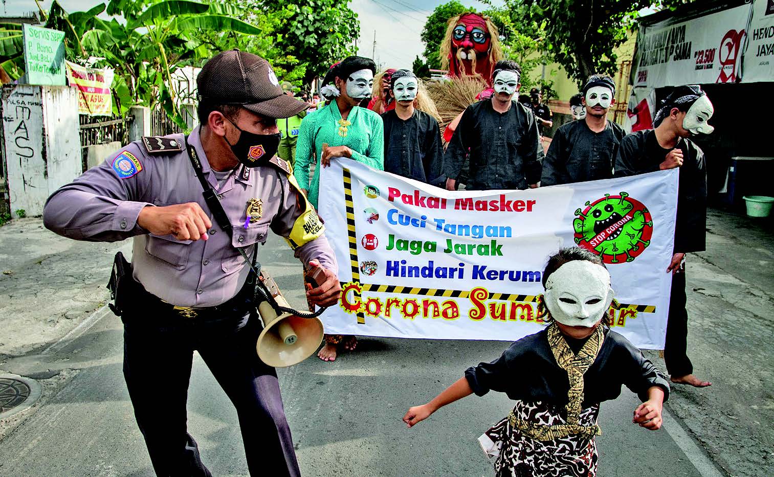 KIRAB SOSIALISASI PROTOKOL KESEHATAN: Kelompok kesenian Barong Kemamang bersama anggota Bhabimkamtibmas berjalan keliling kampung  