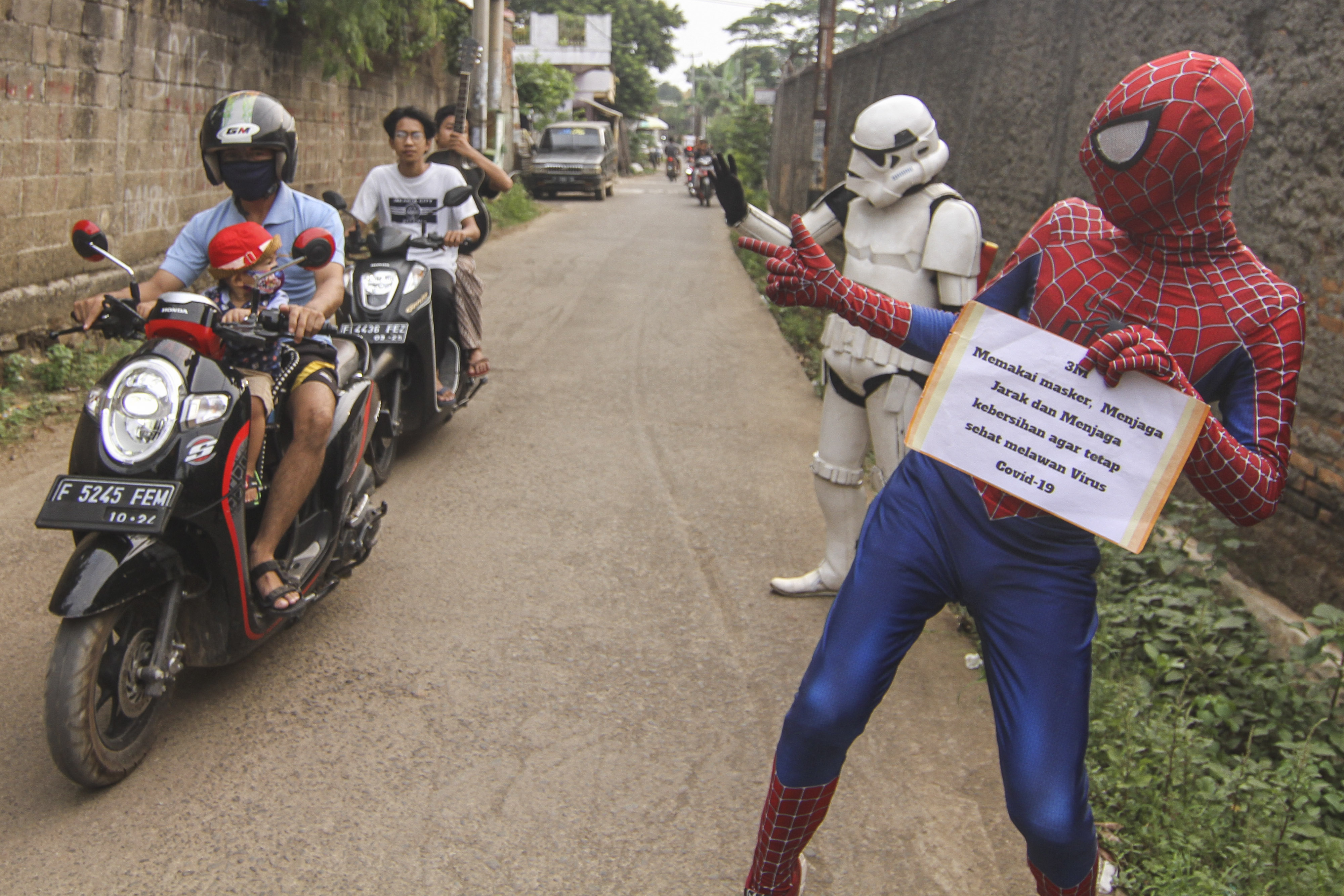 Sejumlah super hero ngamen keliling kampung sambil sosialisasi protokol kesehatan di Kawasan Tapos, Depok