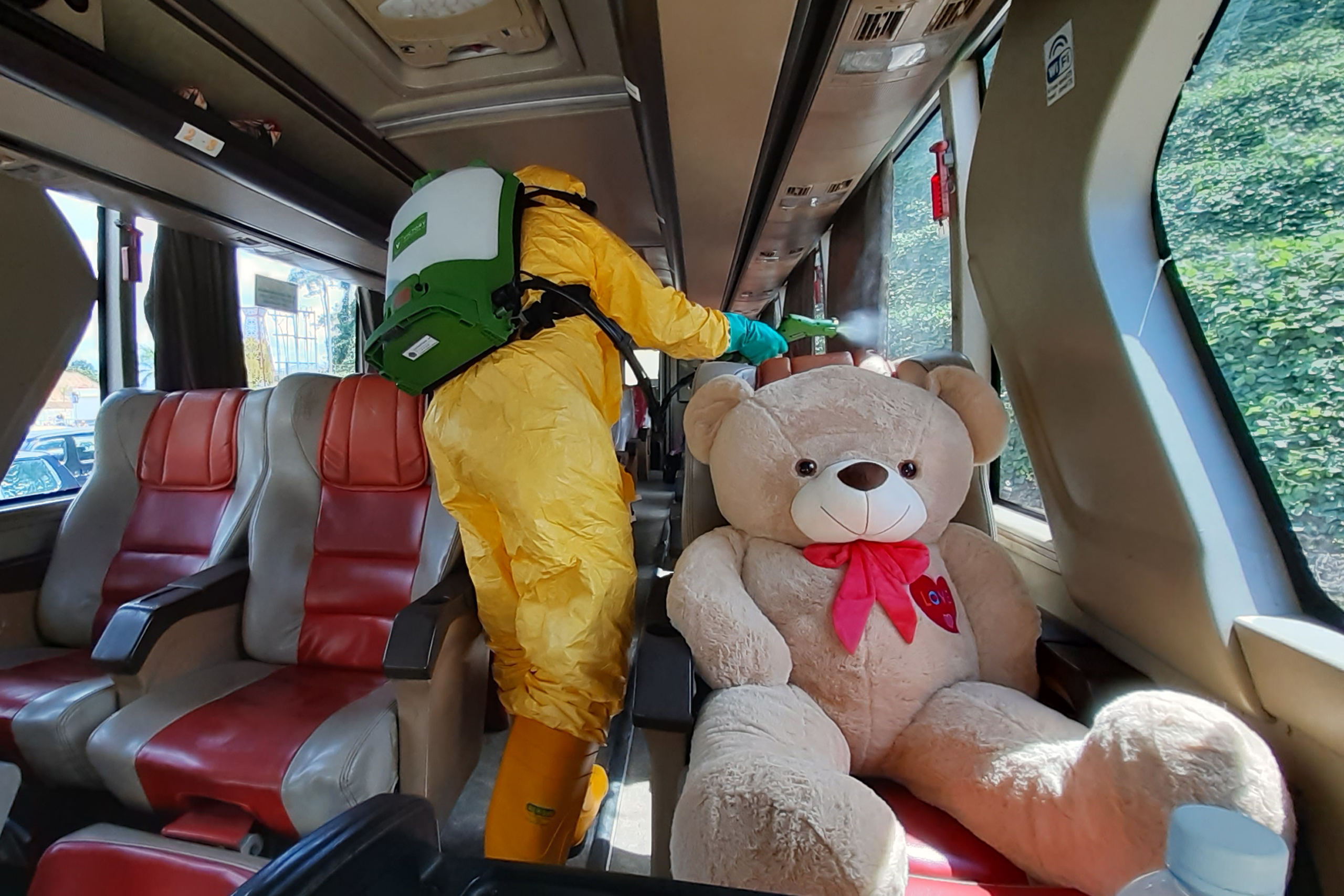 Seorang petugas Kantor Kesehatan Pelabuhan (KKP) Entikong menyemprotkan cairan disinfektan di dalam bus Damri antarnegara dari Brunei .