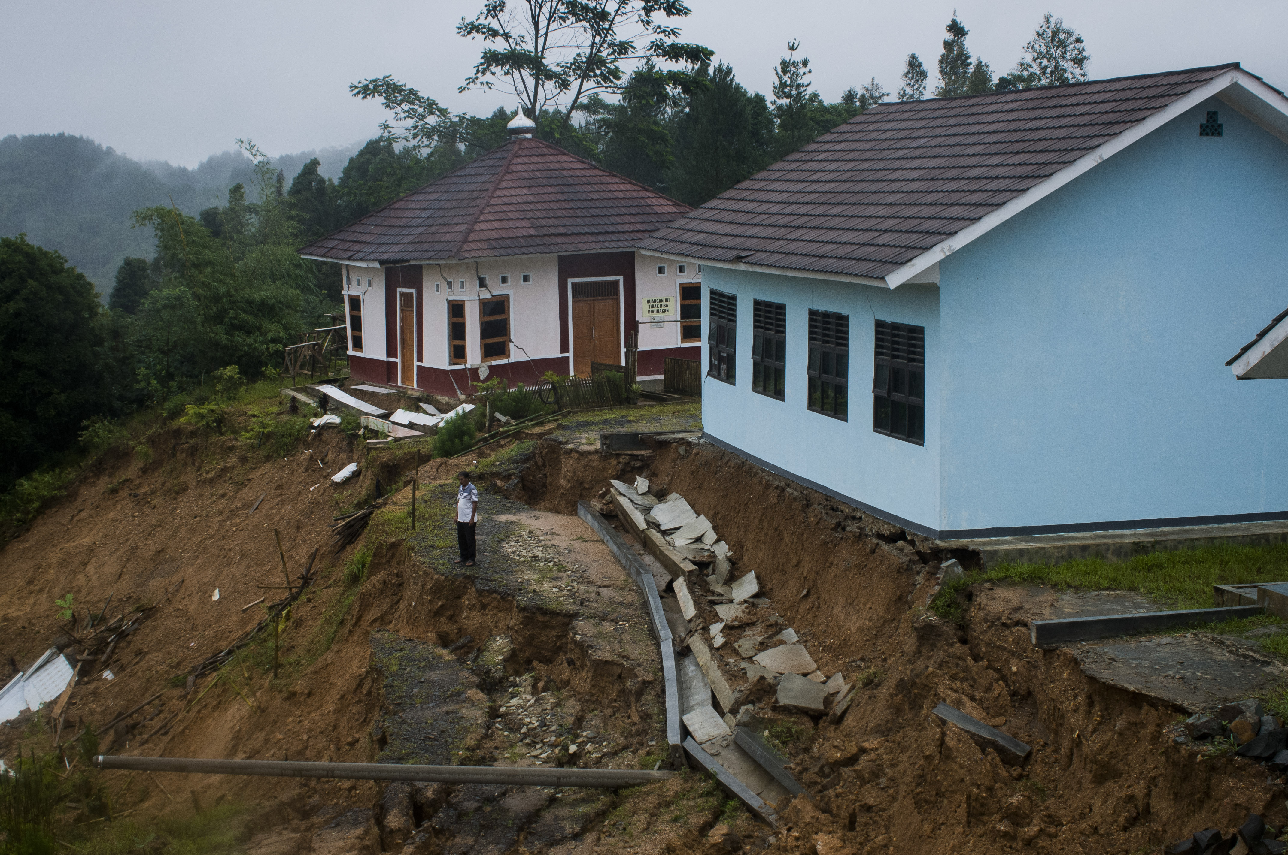 SEKOLAH TERANCAM LONGSOR DI LEBAK: Penjaga sekolah melihat kondisi tanah longsor di sekitar gedung sekolah di SMAN 3 Cibeber, Lebak, Banten,