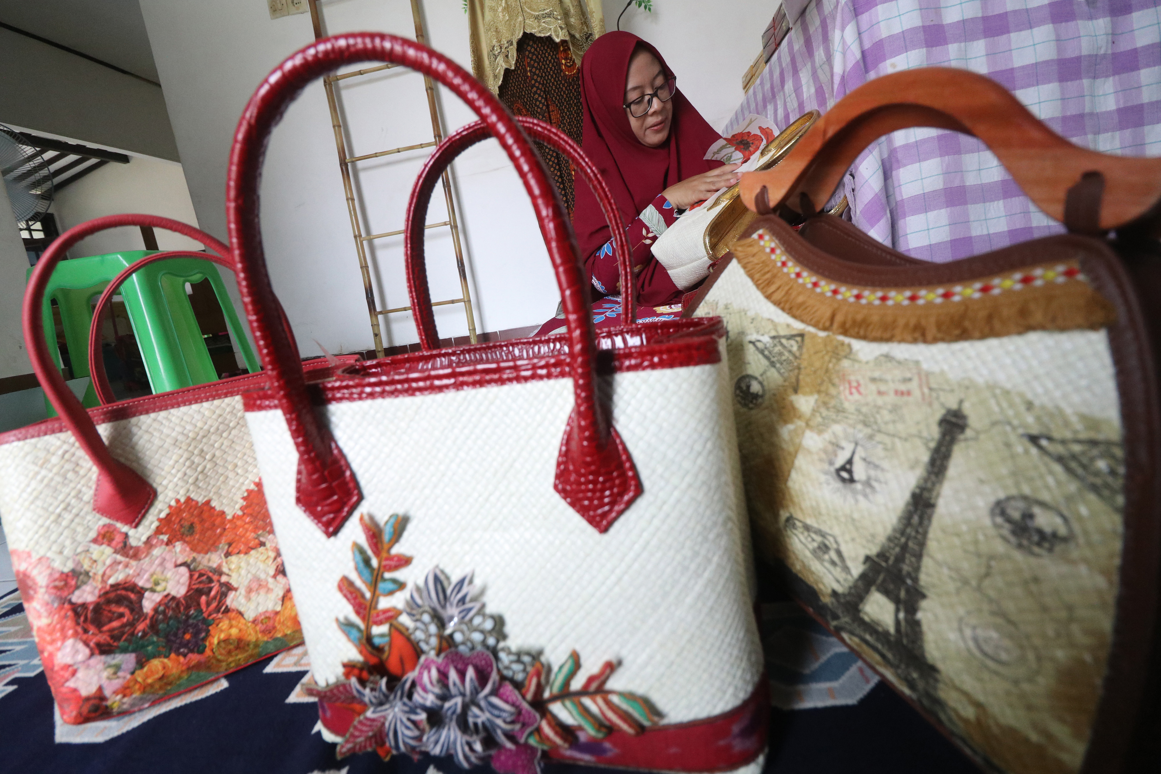 Perajin di Kediri, Jawa Timur, memasang hiasan pada tas anyaman.