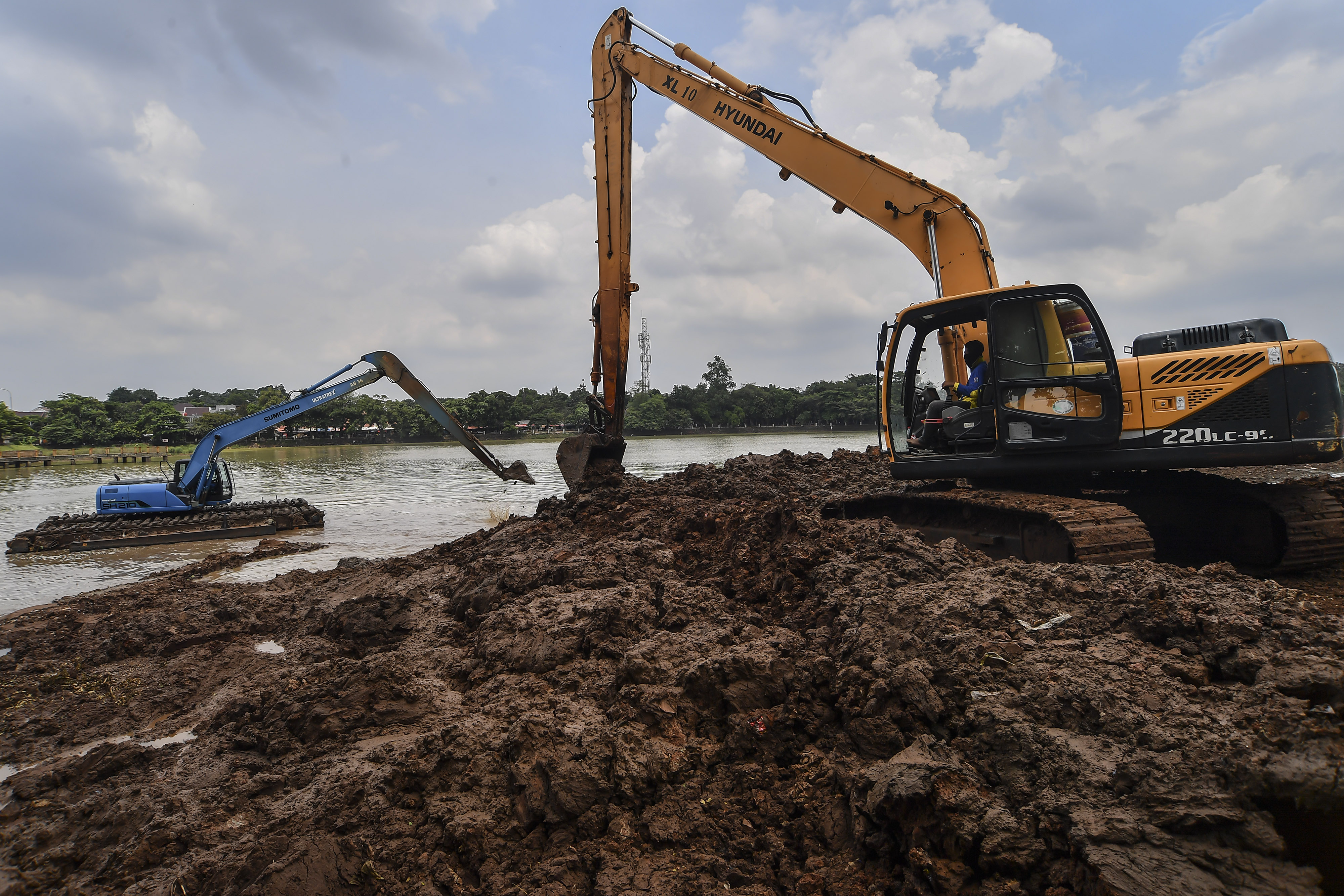 Petugas Sudin Tata Air menggunakan alat berat melakukan pengerukan lumpur di Setu Babakan, Jakarta.