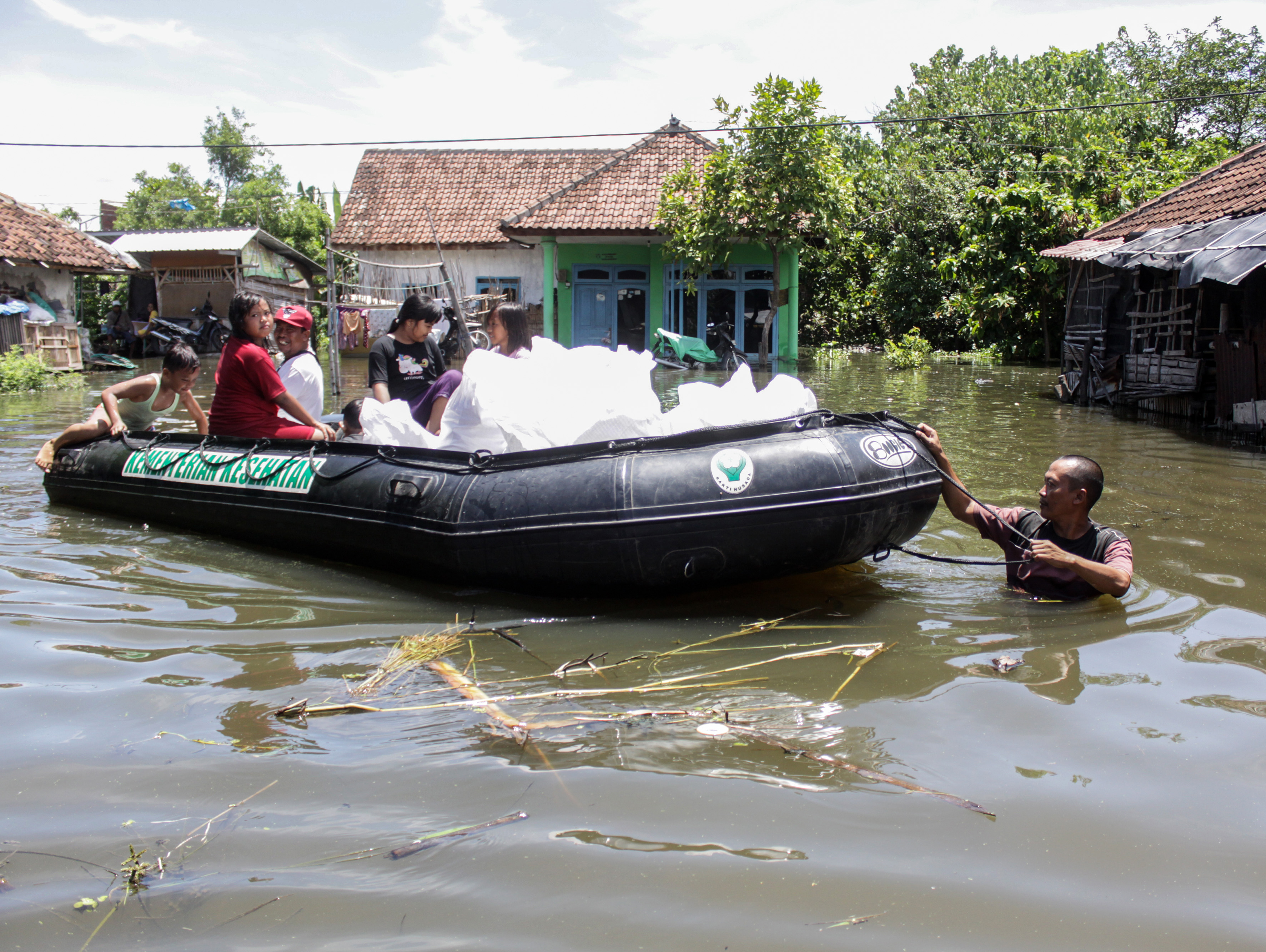 Relawan mendorong perahu karet berisi bantuan untuk disalurkan kepada warga korban banjir di Kedungringin, Beji, Pasuruan, Jatim, kemarin.