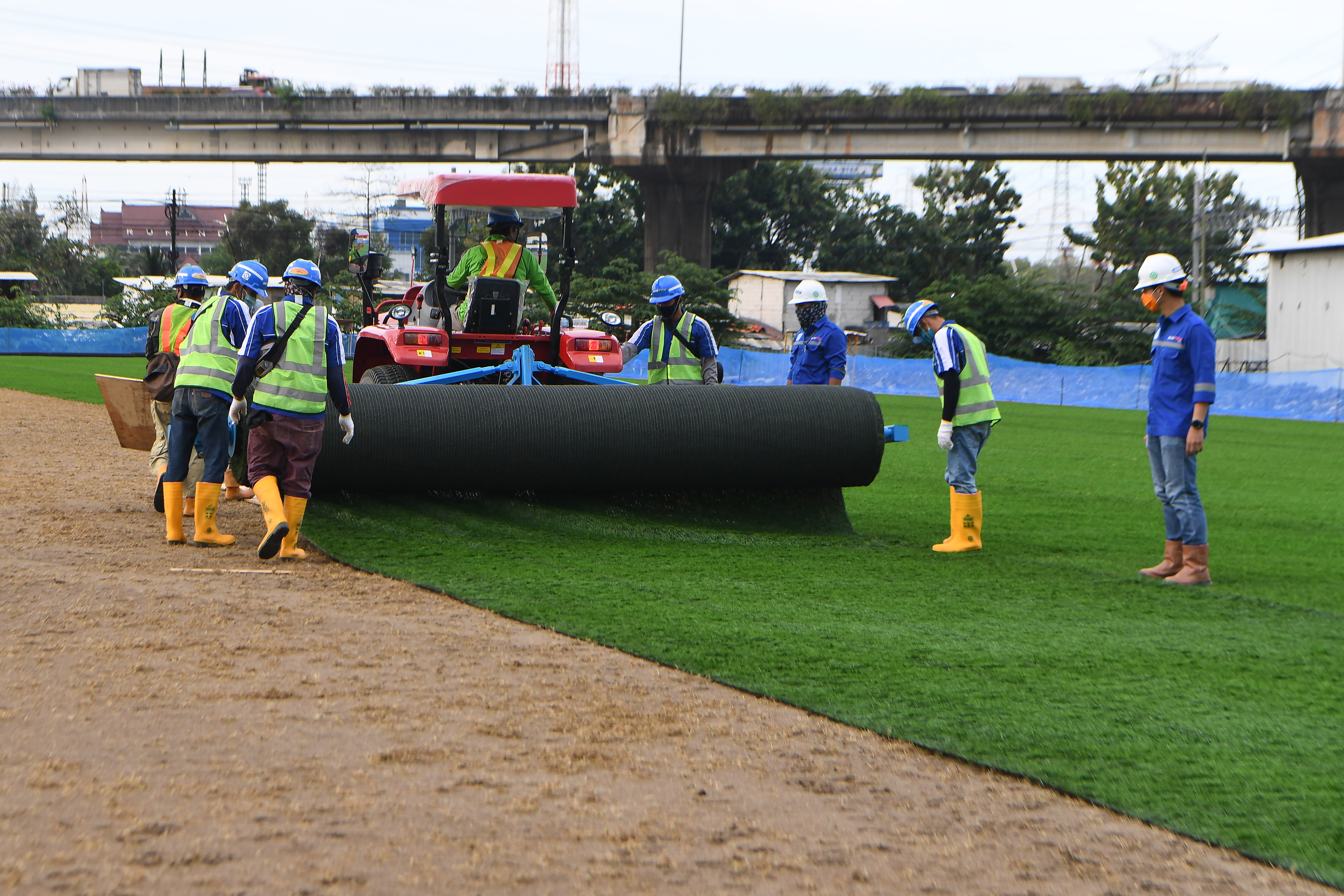 Pekerja menyelesaikan pemasangan rumput untuk lapangan latih di Kompleks Stadion Utama Jakarta International Stadium (JIS), Jakarta.