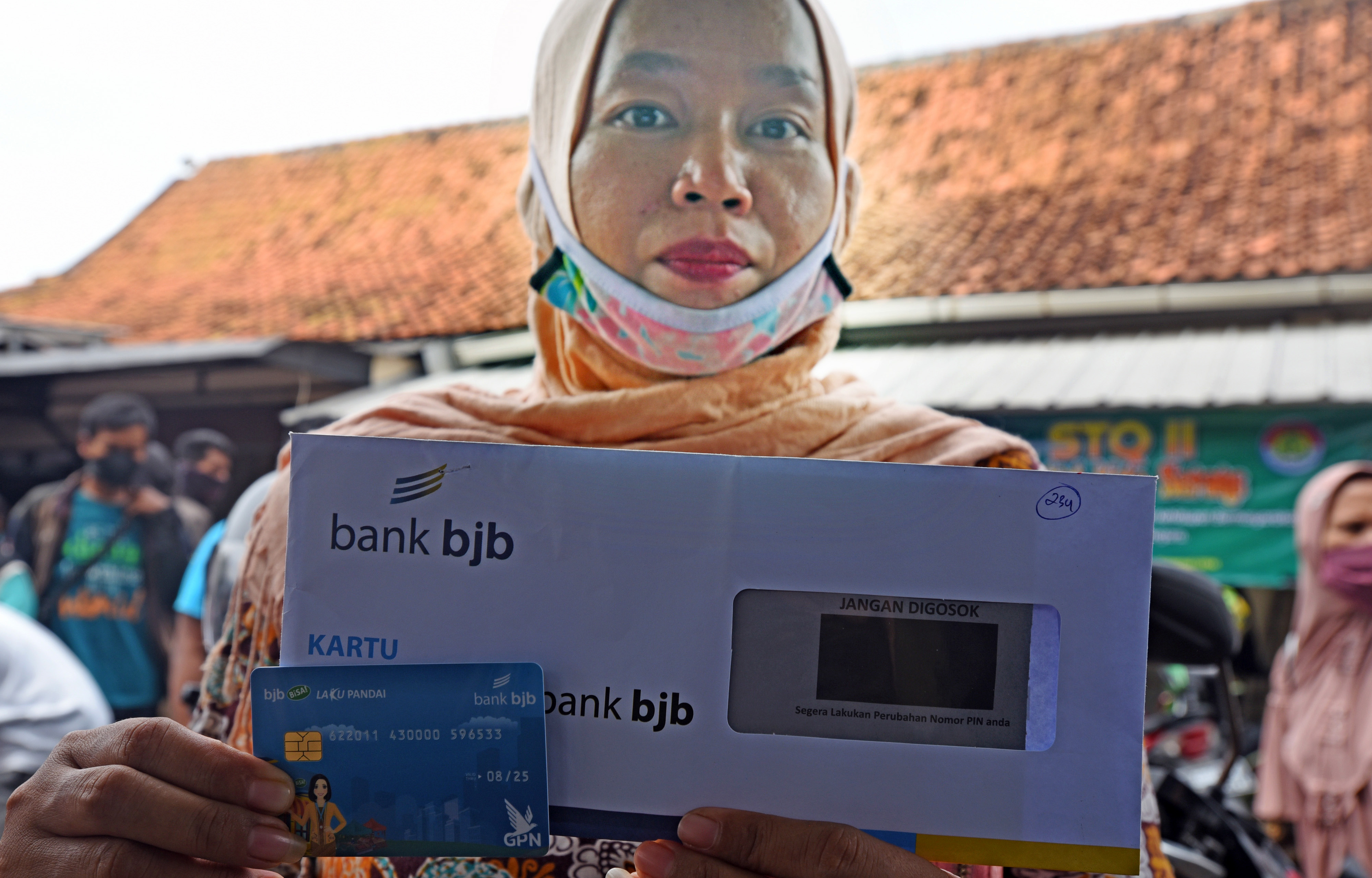 Pelaku usaha mikro memperlihatkan kartu ATM saat pencairan bantuan stimulus di halaman Kantor Disperindag Kota Serang, di Serang, Banten.