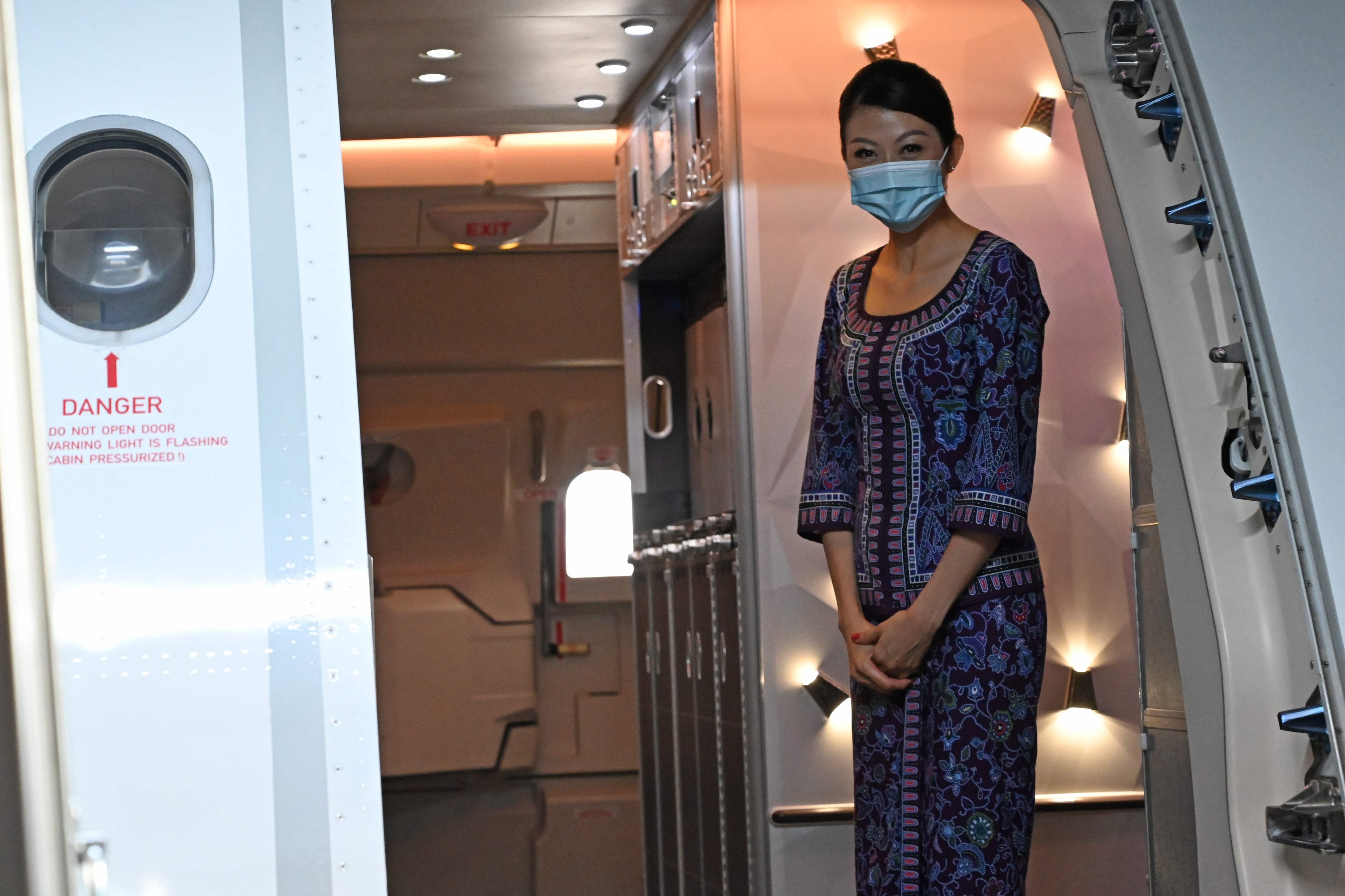 Seorang awak kabin Singapore Airlines menyapa penumpang yang akan masuk ke dalam pesawat.