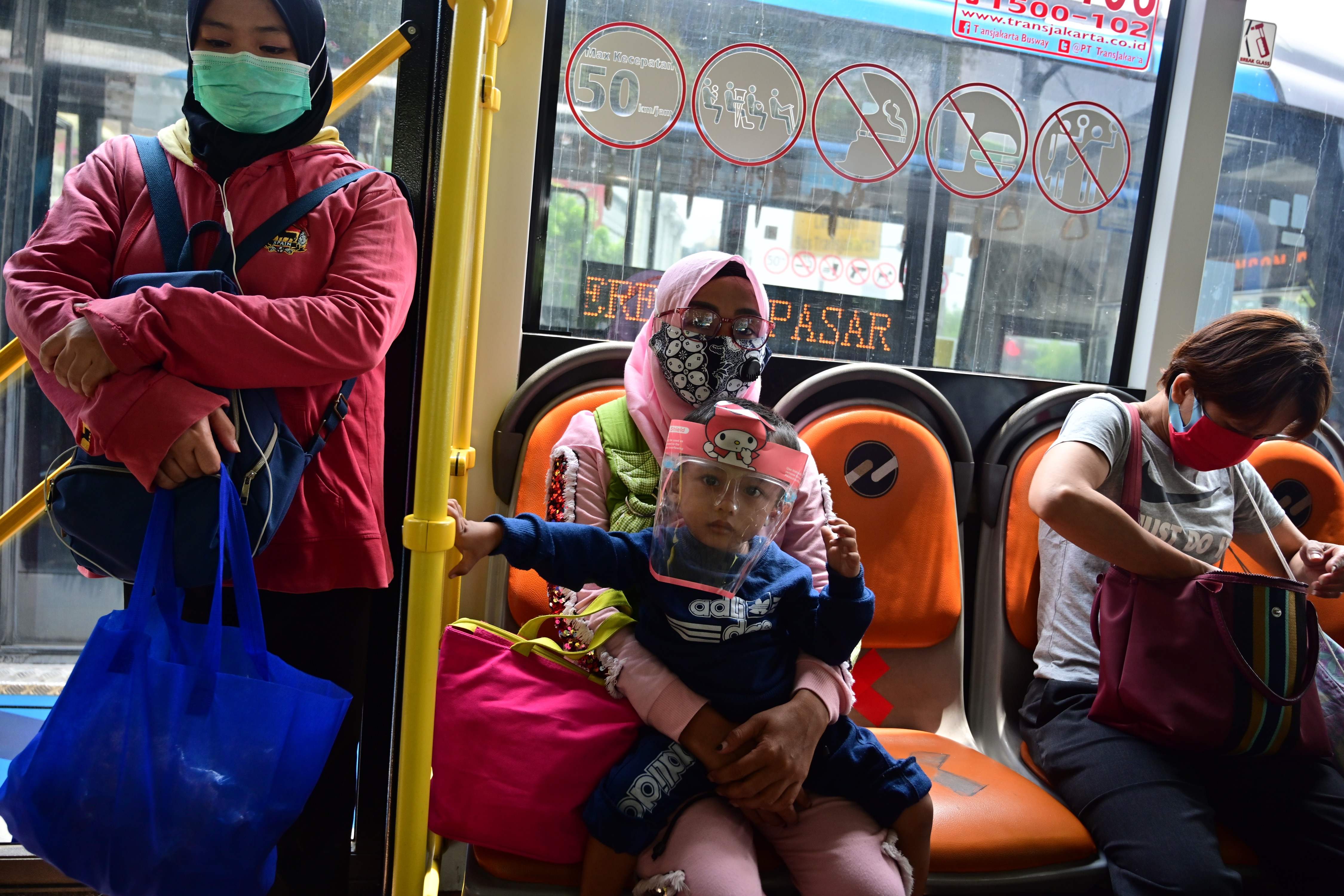 Warga mengenakan masker di dalam bus Trans-Jakarta di Jakarta.
