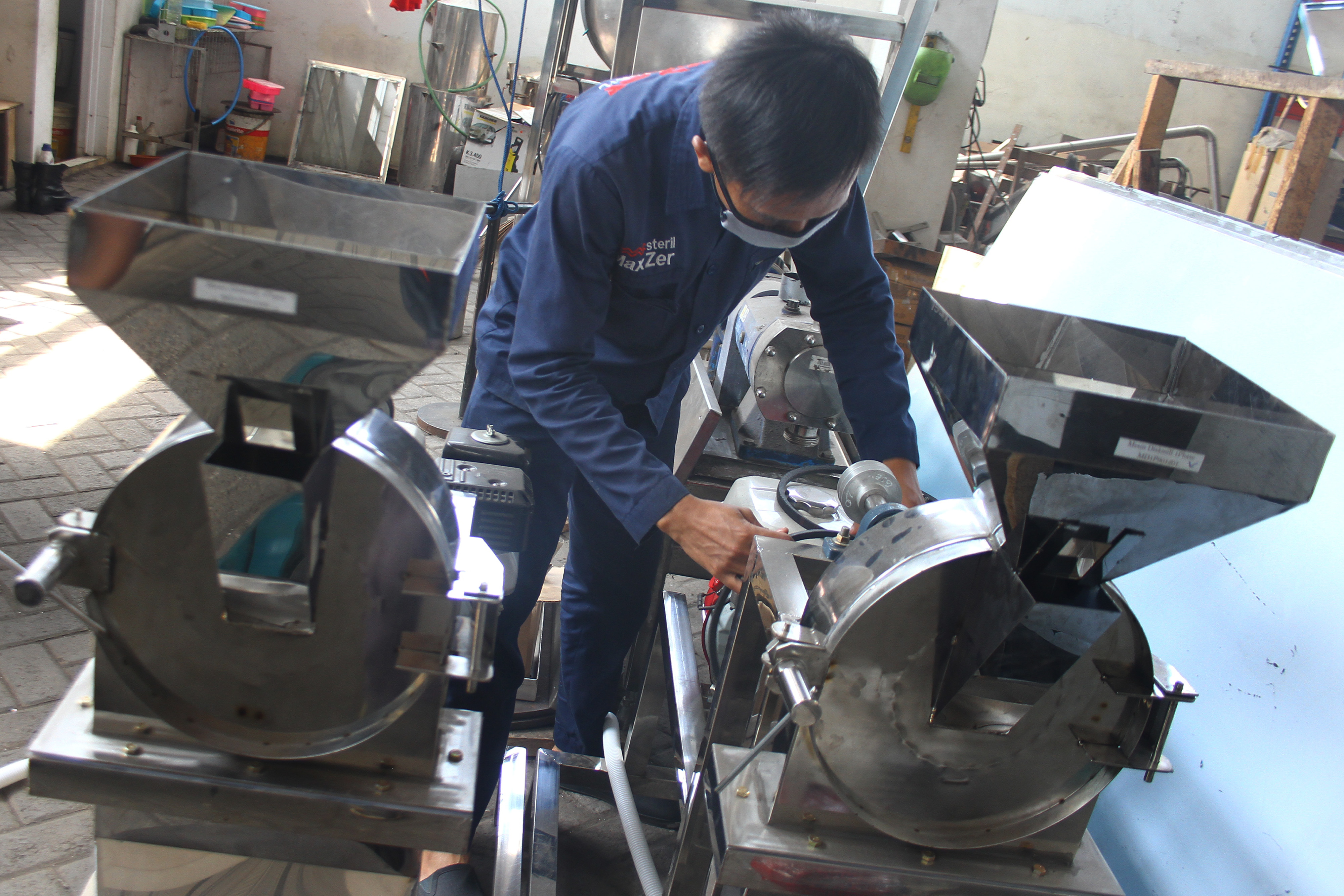 Pekerja memeriksa mesin pengolah makanan