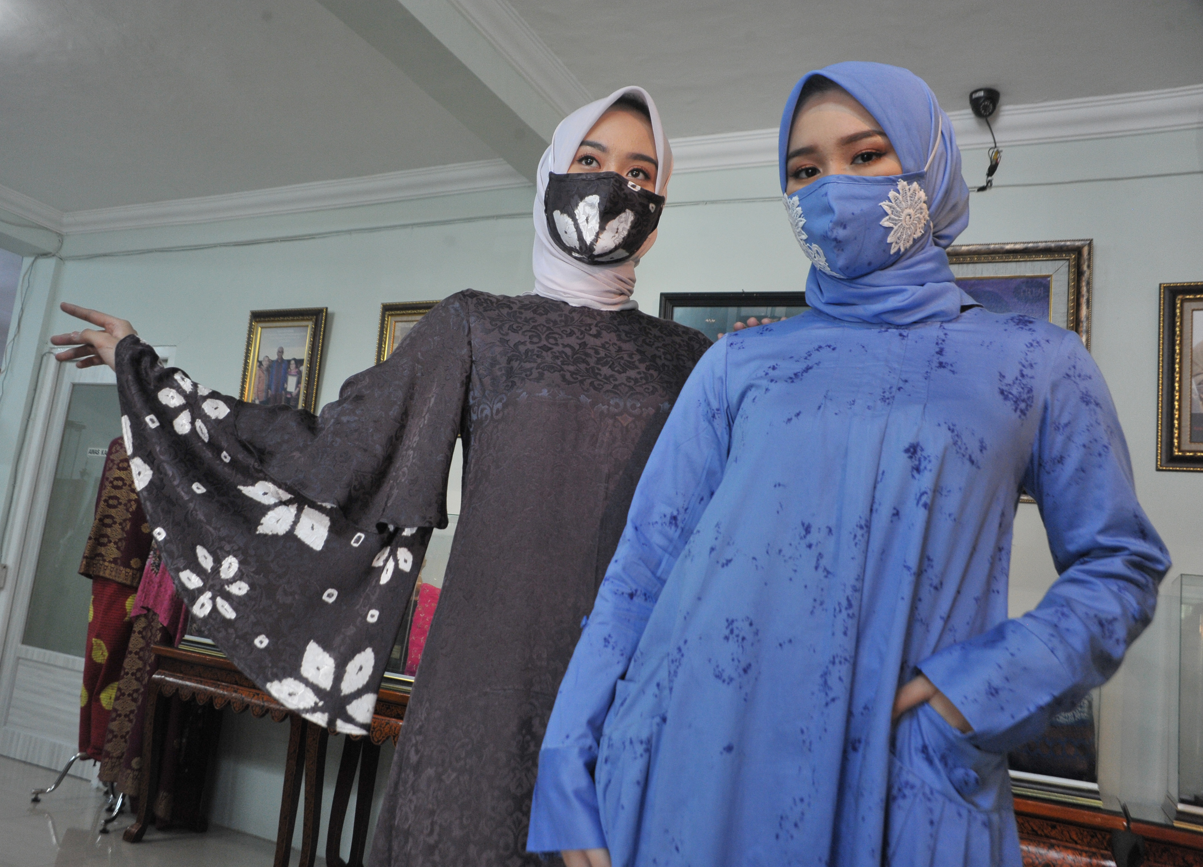 Model menunjukkan busana muslim bermotif jumputan yang senada dengan masker rancangan desainer Tria Gunawan.