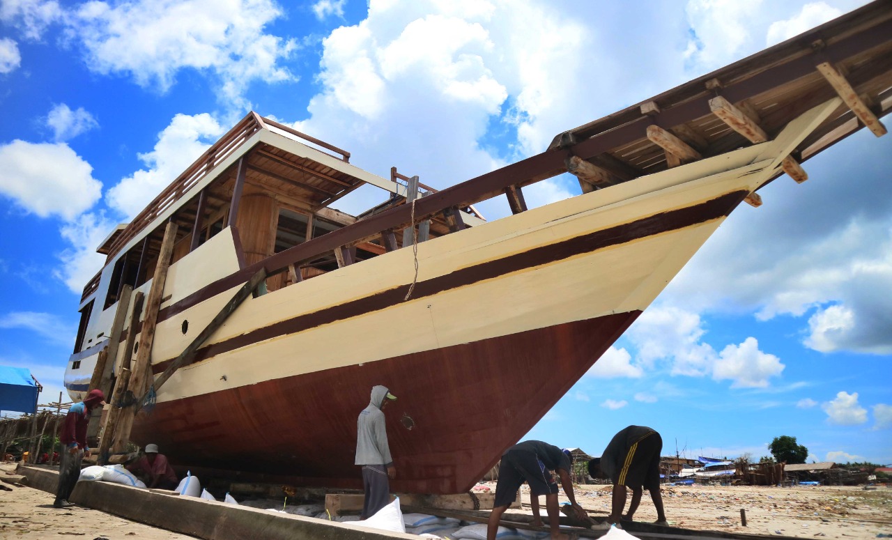 Pekerja tengah menyelesaikan tahap akhir pembuatan pesanan kapal pinisi di Desa Tanah Beru, Bulukumba, Sulawesi Selatan, Sabtu (24/10). 