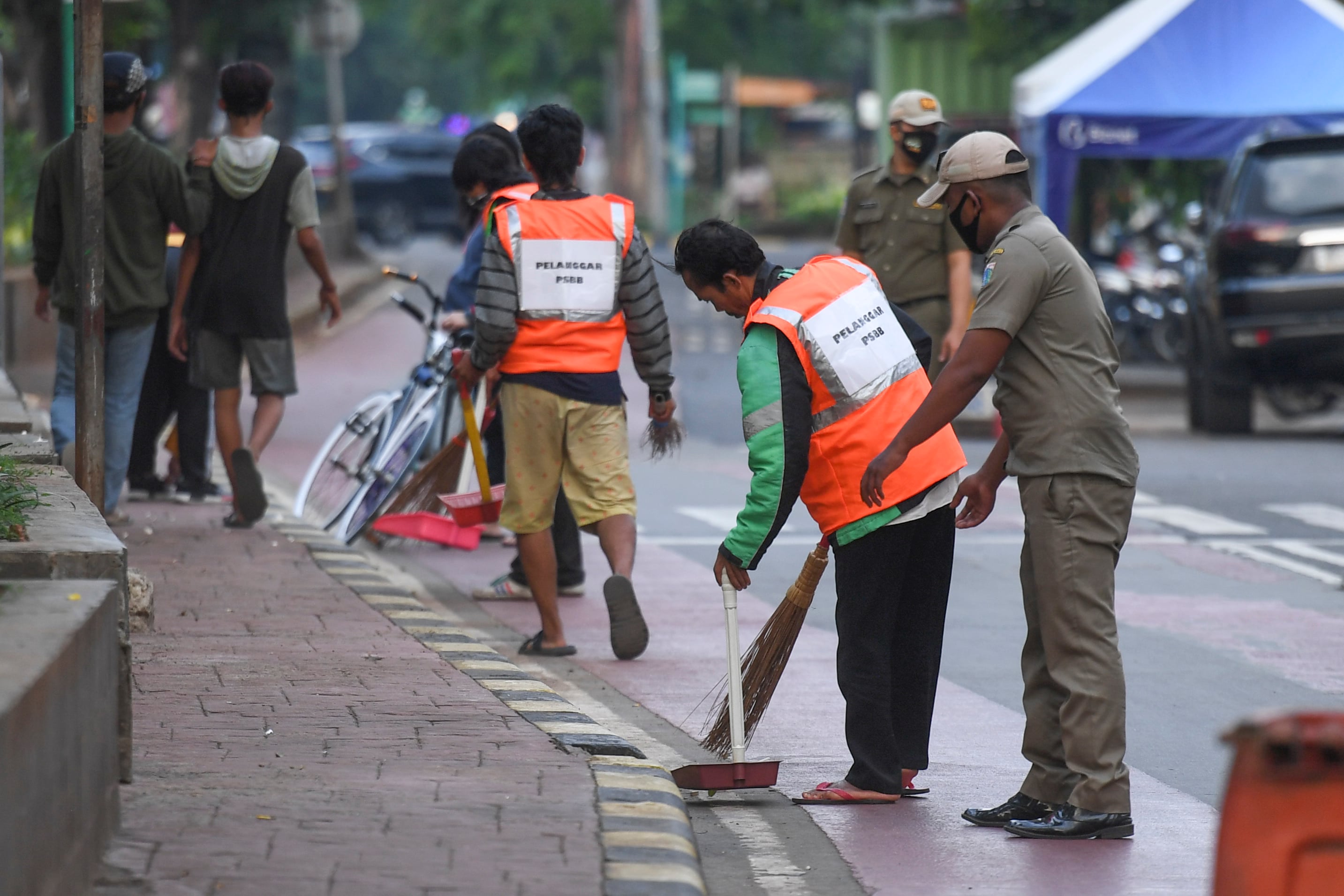 Warga yang melanggar aturan pemberlakuan Pembatasan Sosial Berskala Besar (PSBB) dihukum menyapu