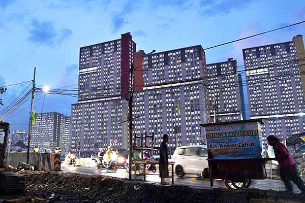 Warga beraktivitas dengan latar belakang Rumah Sakit Darurat COVID-19 Rumah Sakit Darurat COVID-19 Wisma Atlet di Jakarta, kemarin.