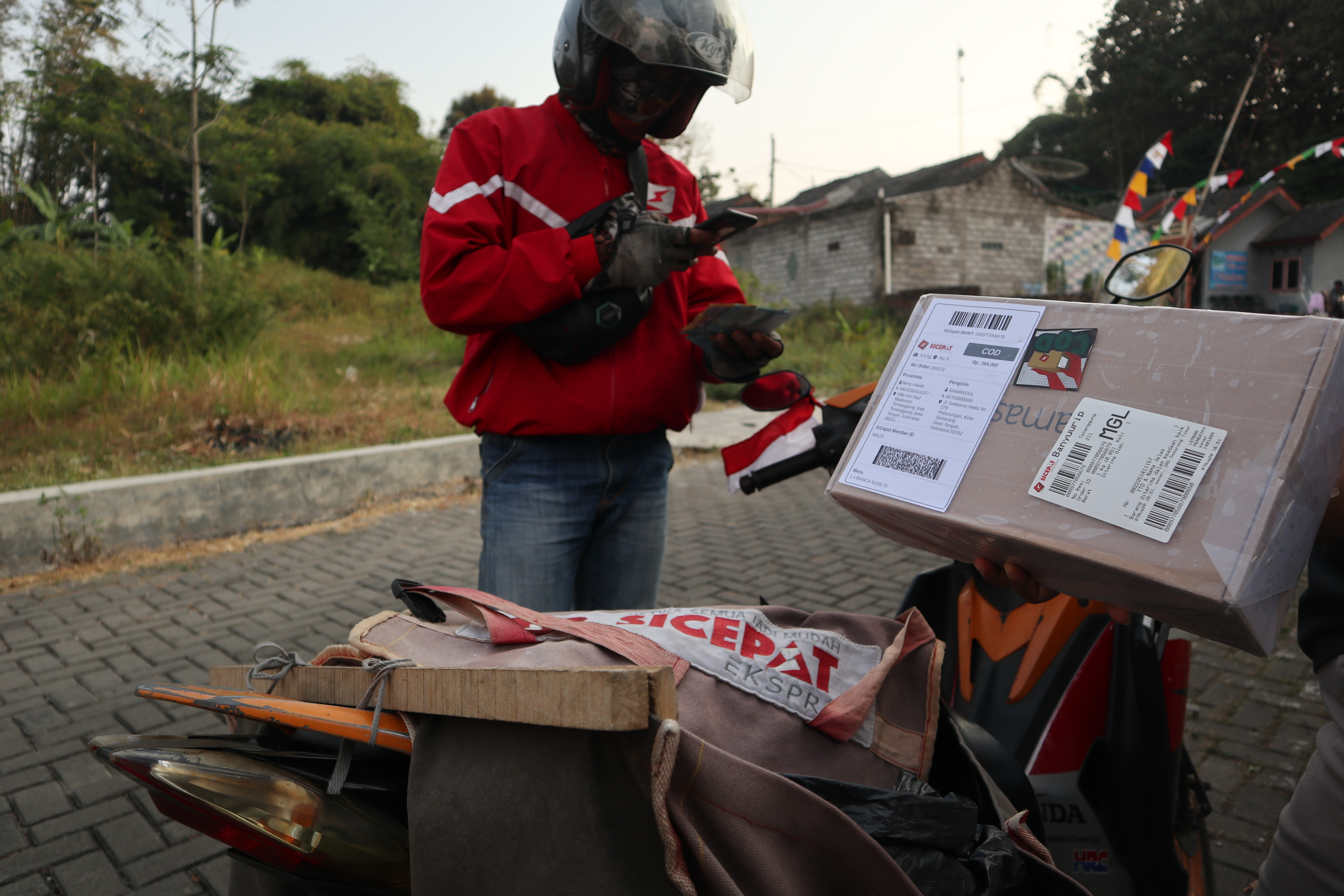 Seorang kurir mengantarkan kiriman barang ke rumah warga Temanggung, Minggu (9/8/2020).