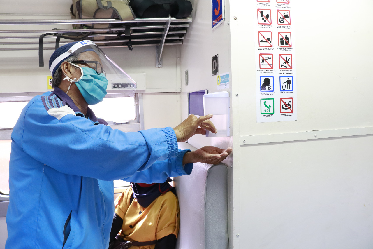 Penumpang kereta api di Kota Palembang mencuci tangan dengan handsanitizer, memakai masker dan pelindung wajah selama di dalam kereta.