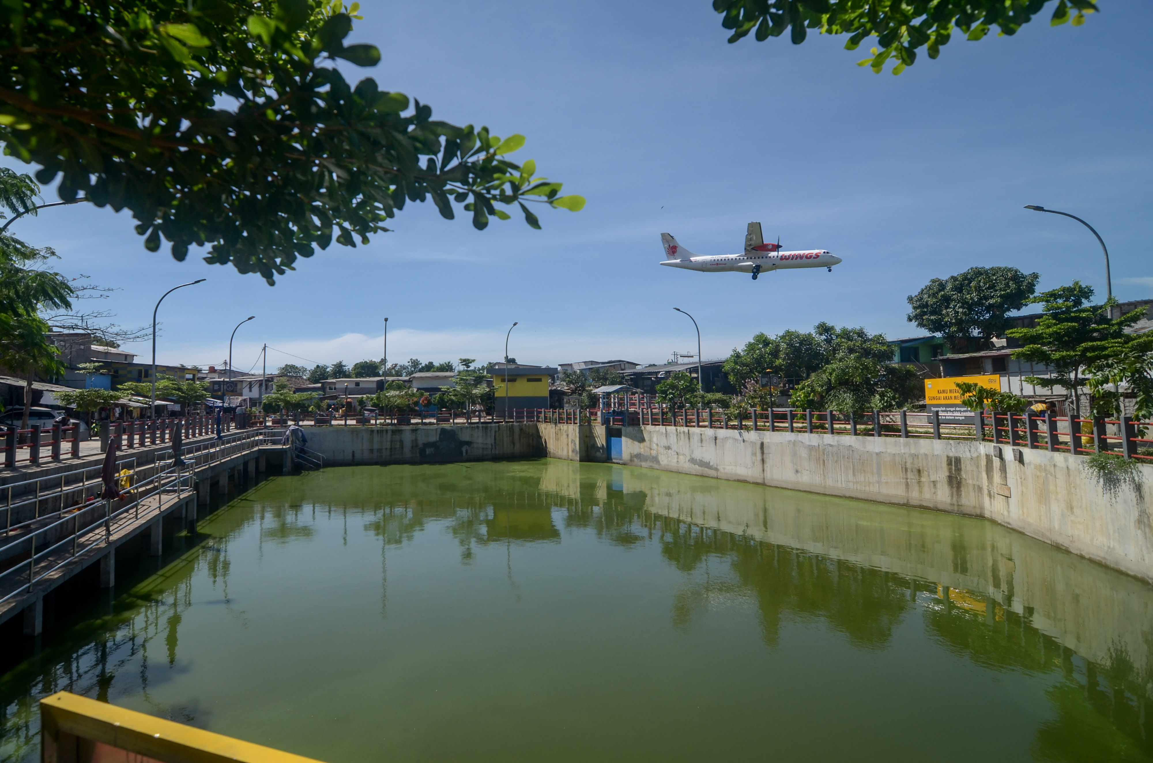 Sebuah pesawat komersial melintas di dekat Kolam Retensi Sirnaraga di Bandung, Jawa Barat, Selasa (14/1/2020)