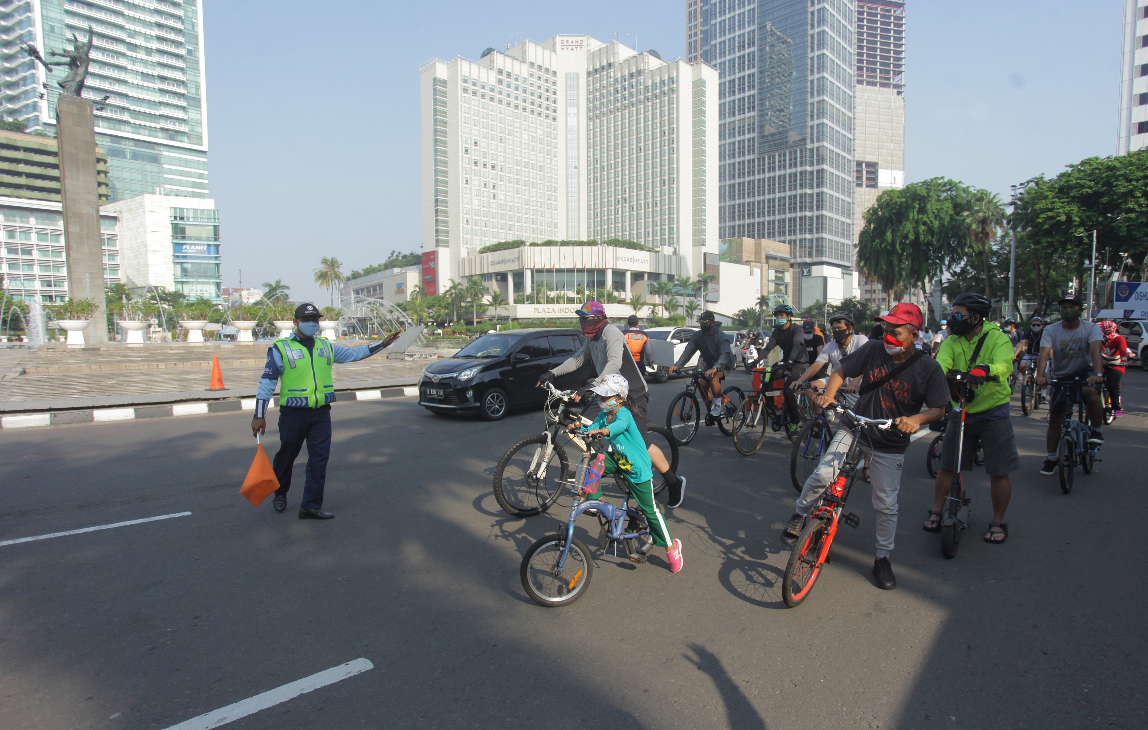 Warga berseeda dengan menggunakan masker di Bundaran HI, Jakarta