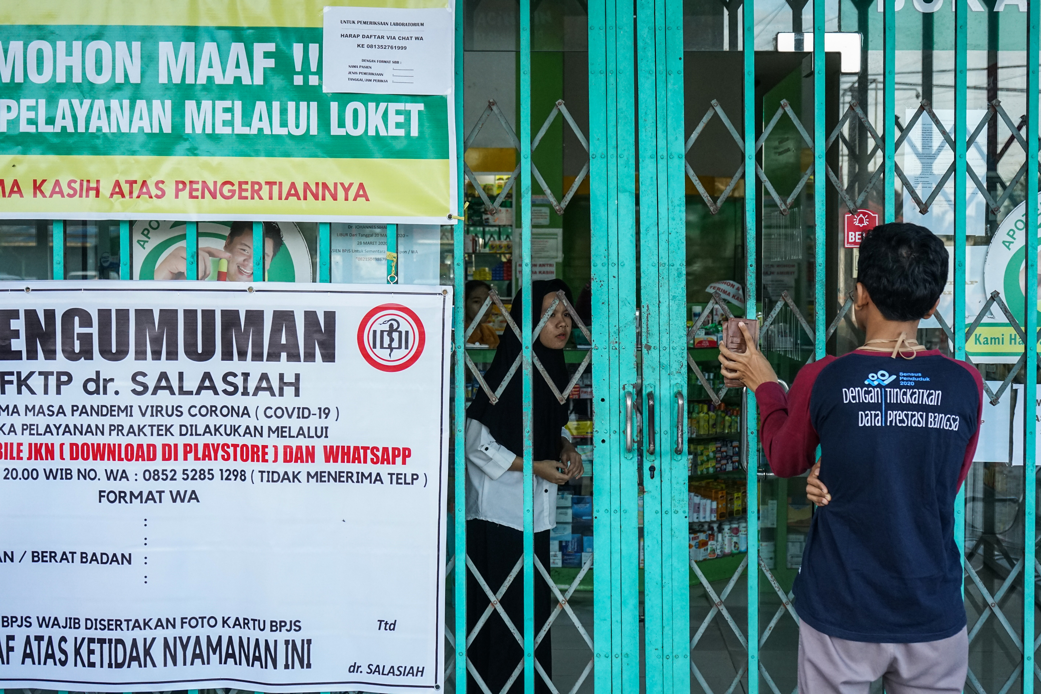  Pegawai apotek melayani pembeli dari batas pagar di salah satu apotek, Palangkaraya, Kalimantan Tengah, Sabtu (4/4)