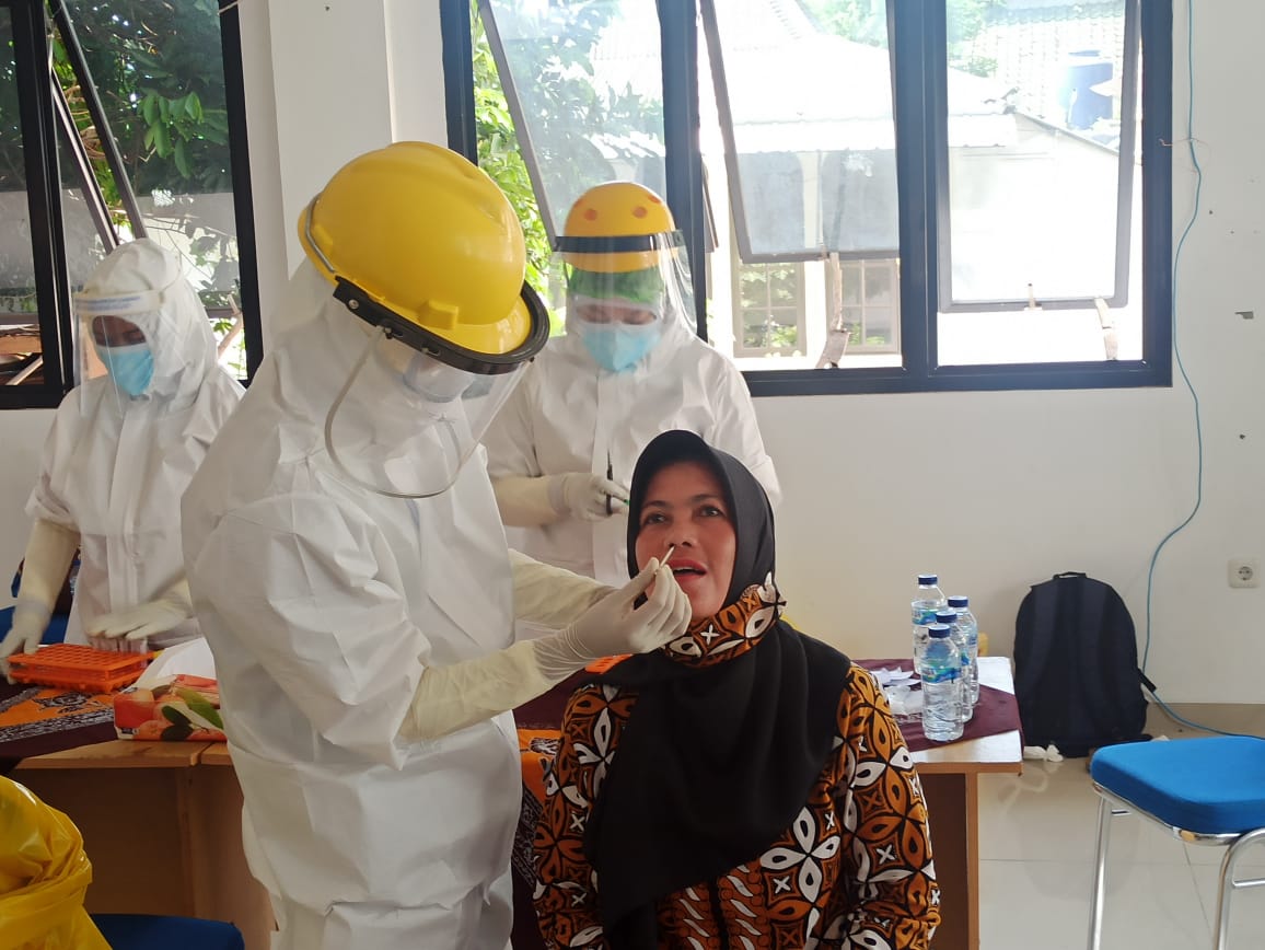 Seorang petugas kesehatan melakukan swab test kepada tenaga pendidikan.