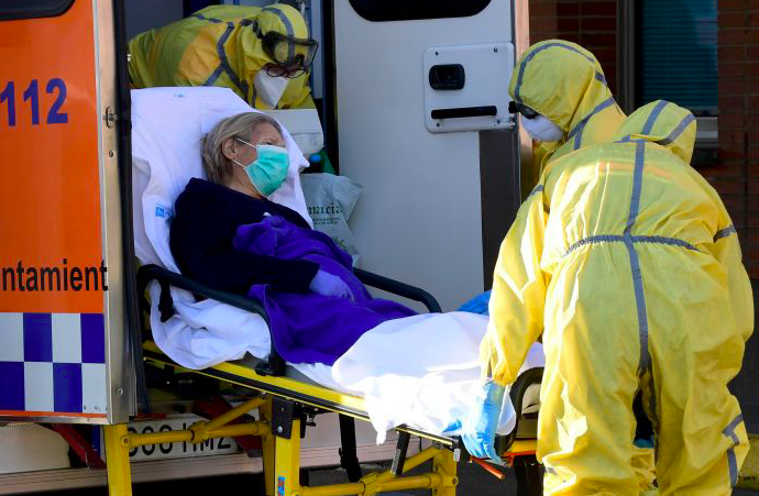 Petugas kesehatan menurunkan pasien virus korona setibanya mereka di Rumah Sakit Severo Ochoa, Leganes, Spanyol.