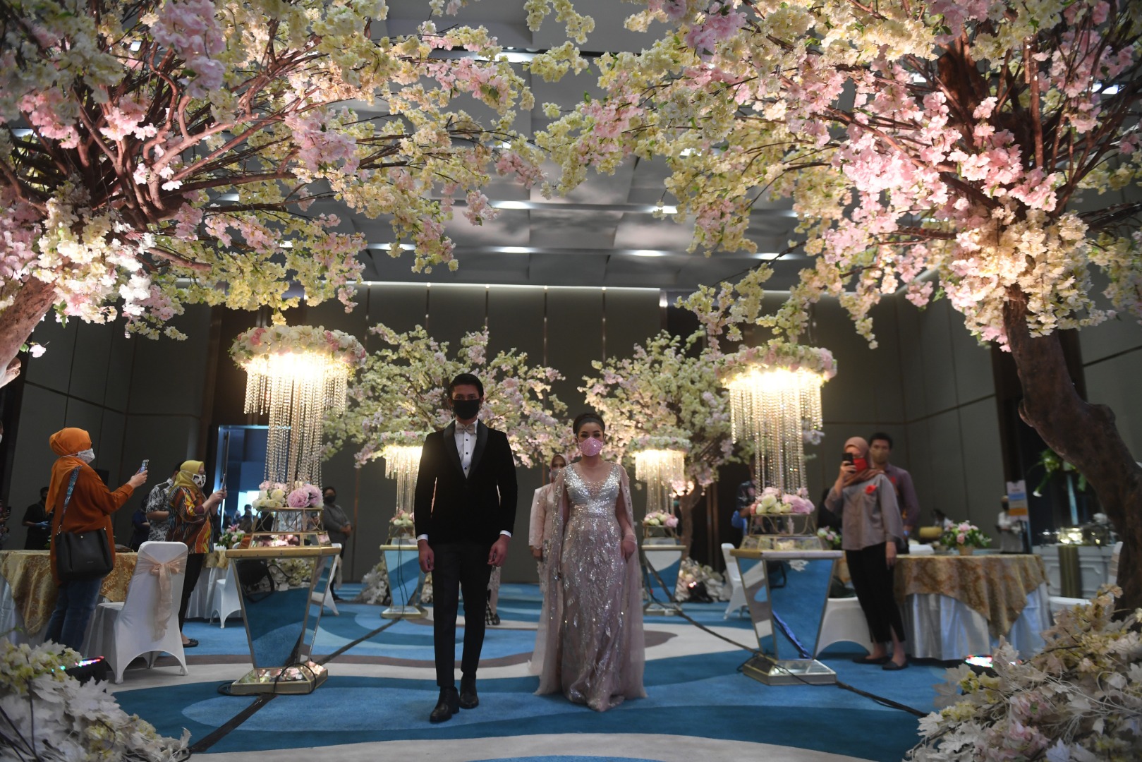 Pasangan pengantin mengenakan masker dalam simulasi pernikahan di era normal baru di Jakarta