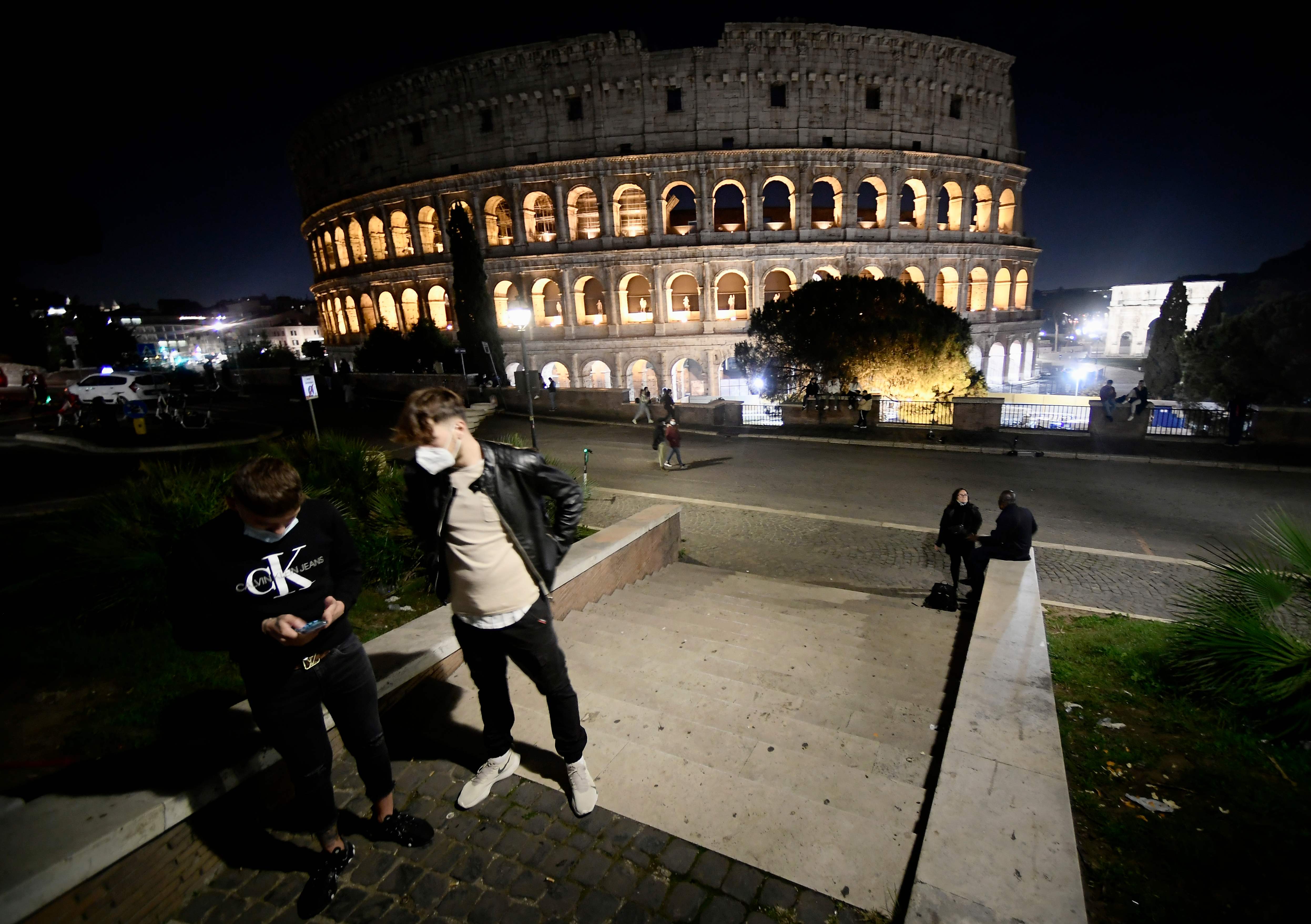 Warga mengenakan masker beraktivitas di dekat Colosseum di Roma, Italia.