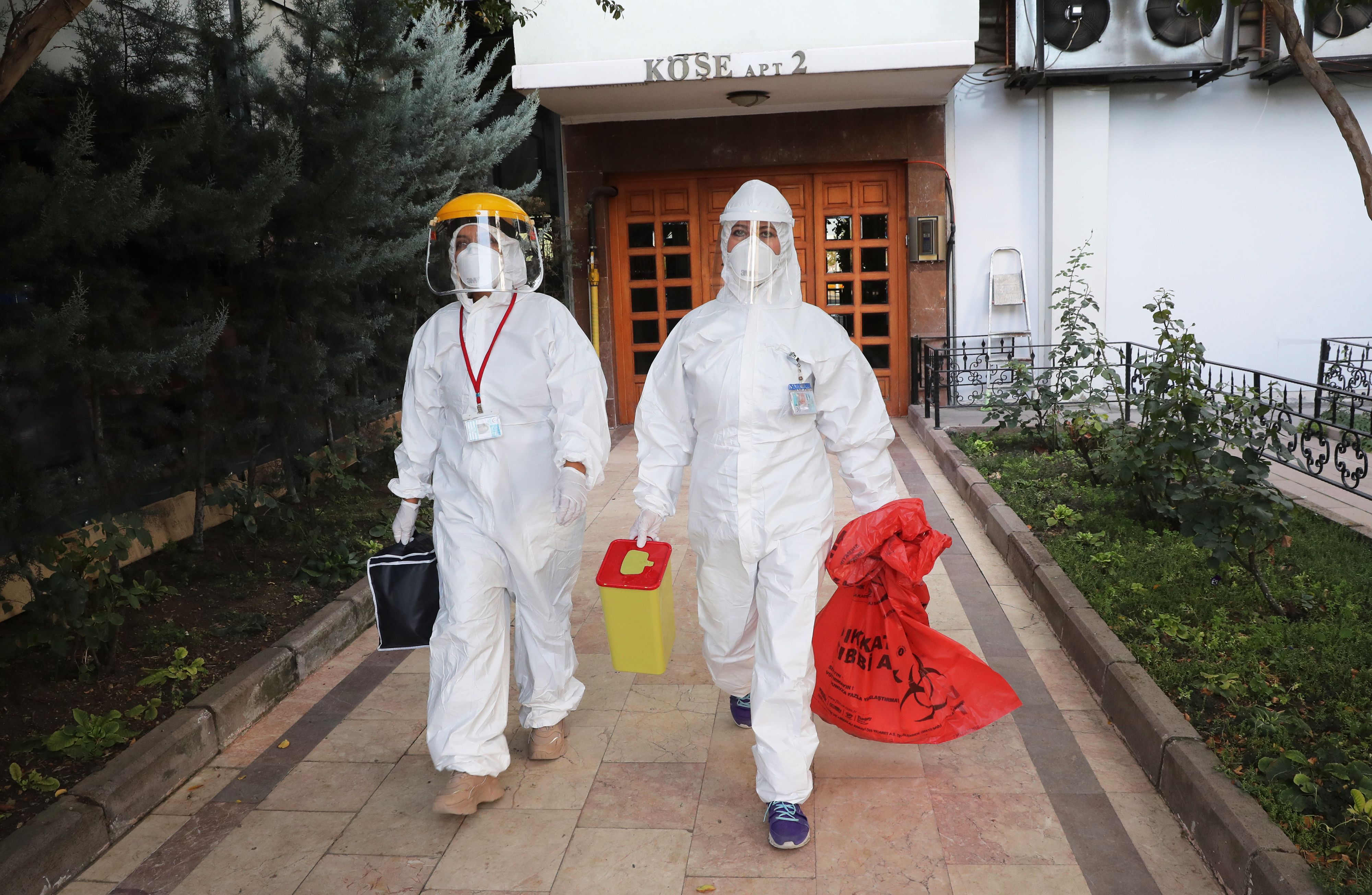 Petugas meninggalkan sebuah komplek apartemen di Ankara, Turki setelah mengambil sampel covid-19 dari warga.