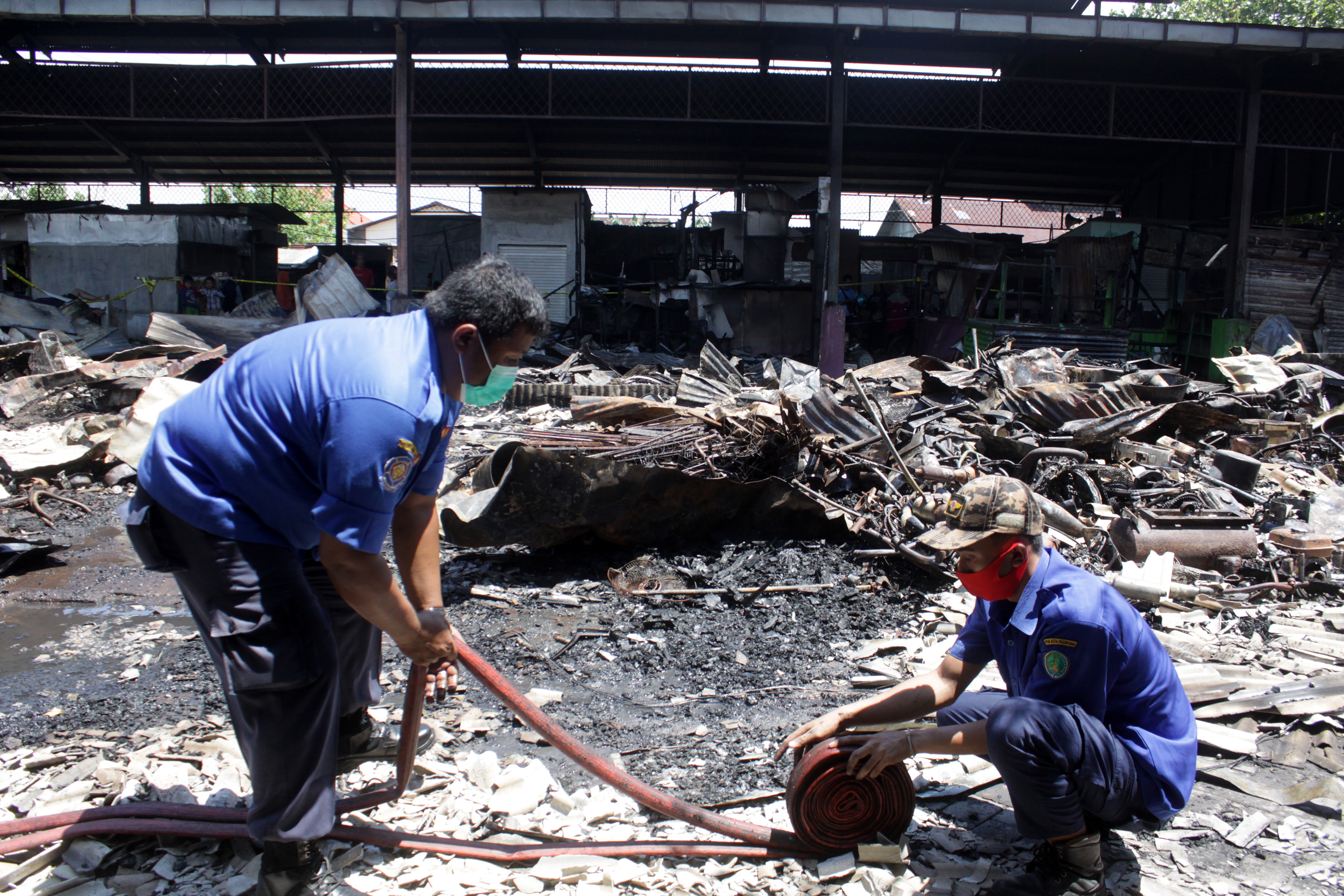 Petugas Damkar membereskan peralatan paska kebakaran pasar.
