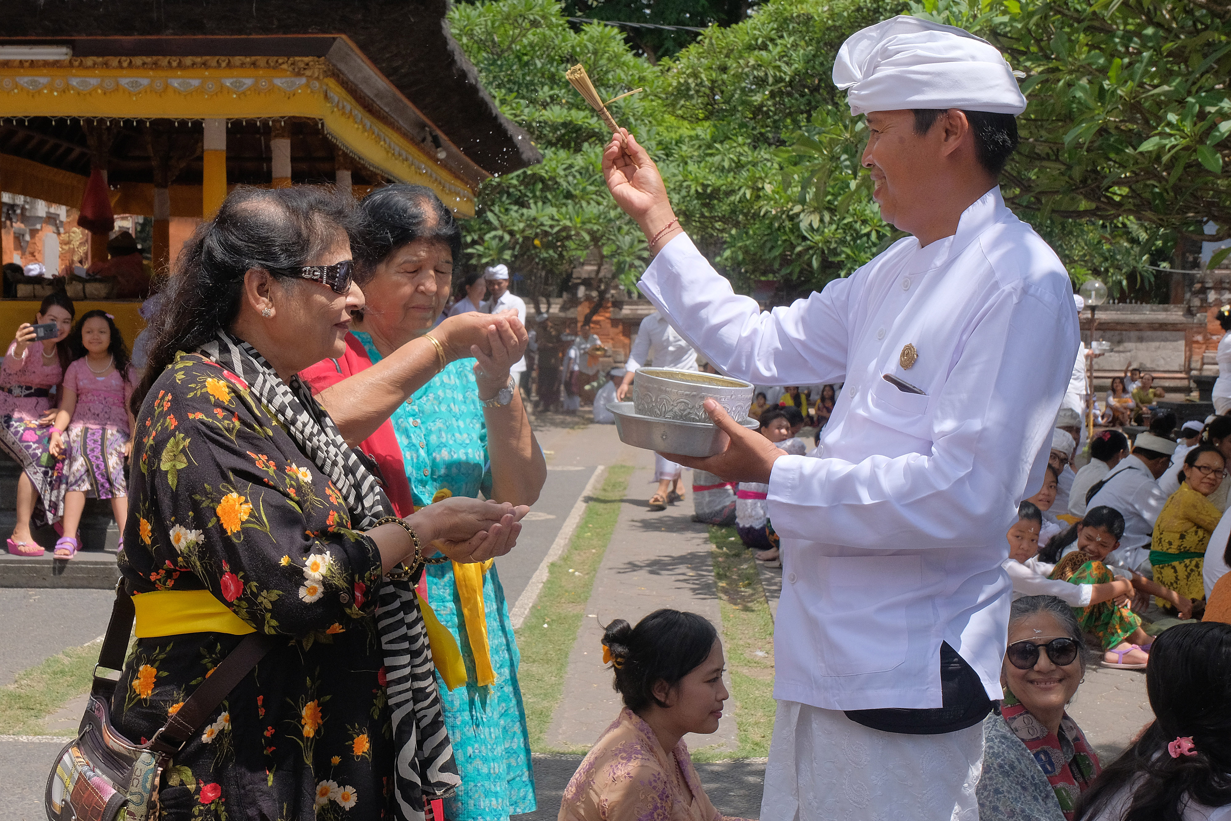 Pemuka agama Hindu memercikan air suci kepada dua wisatawan asal India dalam persembahyangan di Pura Agung Jagatnatha, Denpasar, Bali.
