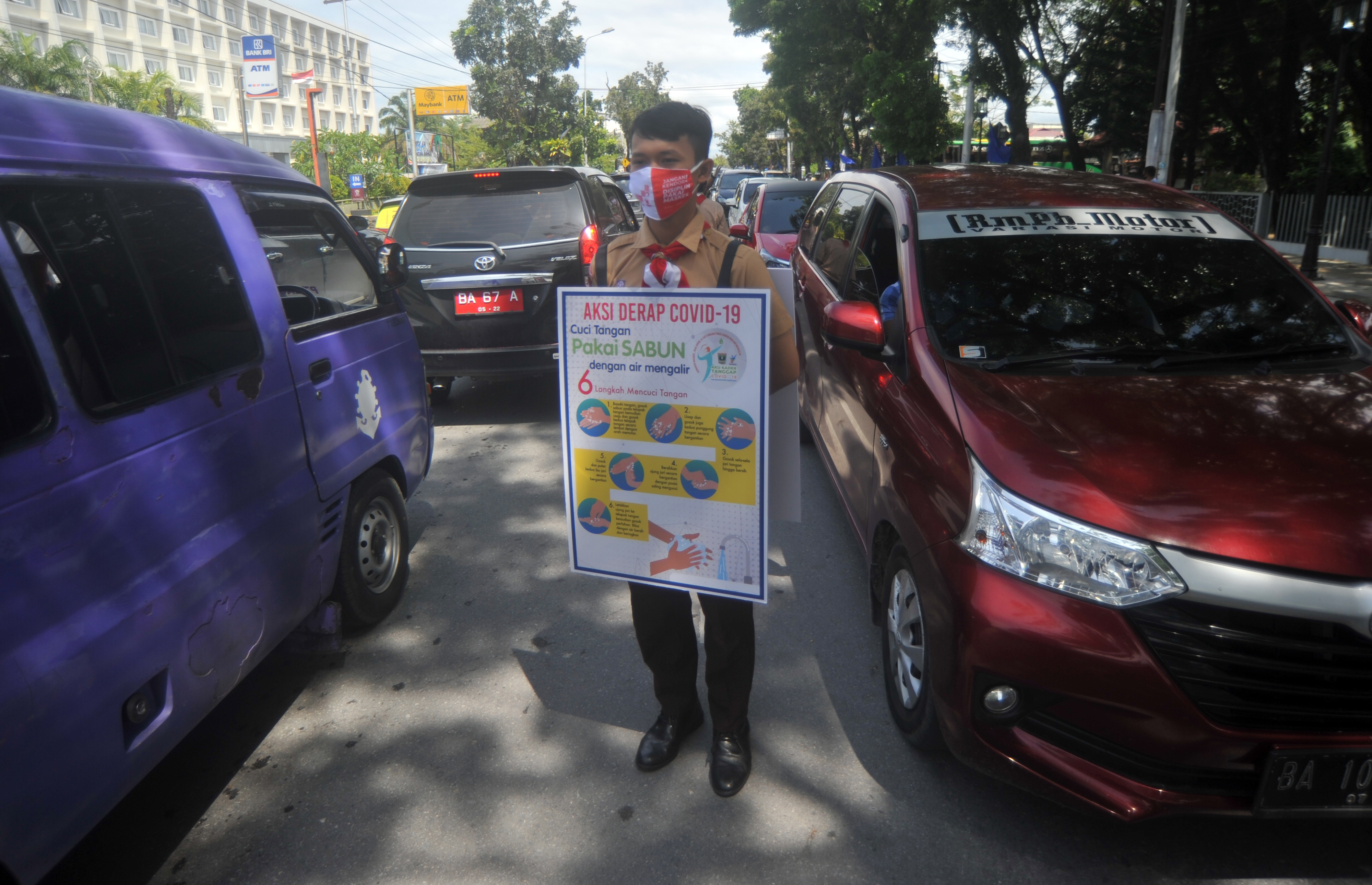 Anggota Pramuka membawa papan sosialisasi cara mencuci tangan pakai sabun saat digelarnya Aksi Derap COVID 19