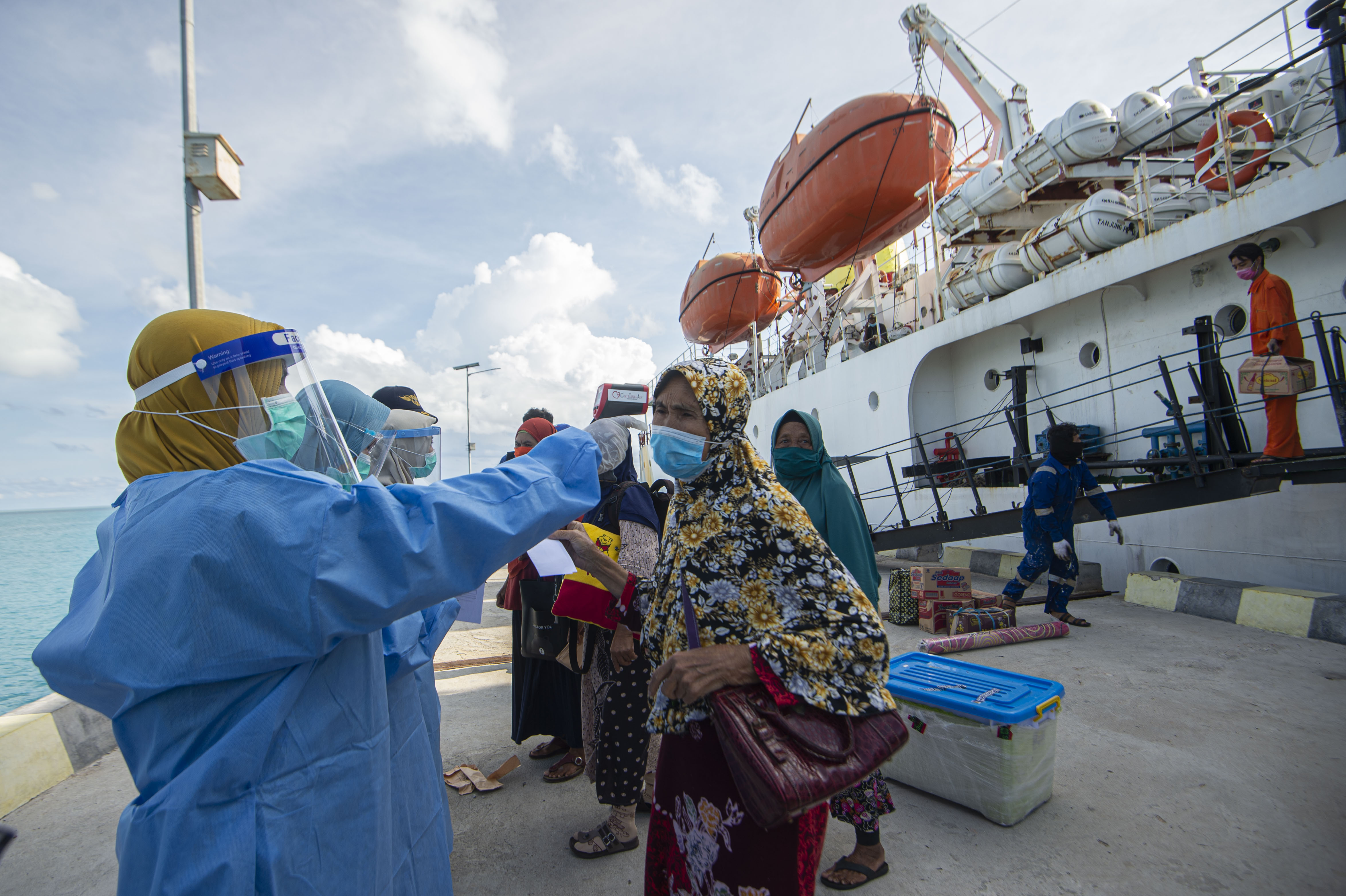 Petugas mengukur suhu tubuh penumpang KM Sabuk Nusantara 83 di dermaga pelabuhan Natuna, Kepulauan Riau.
