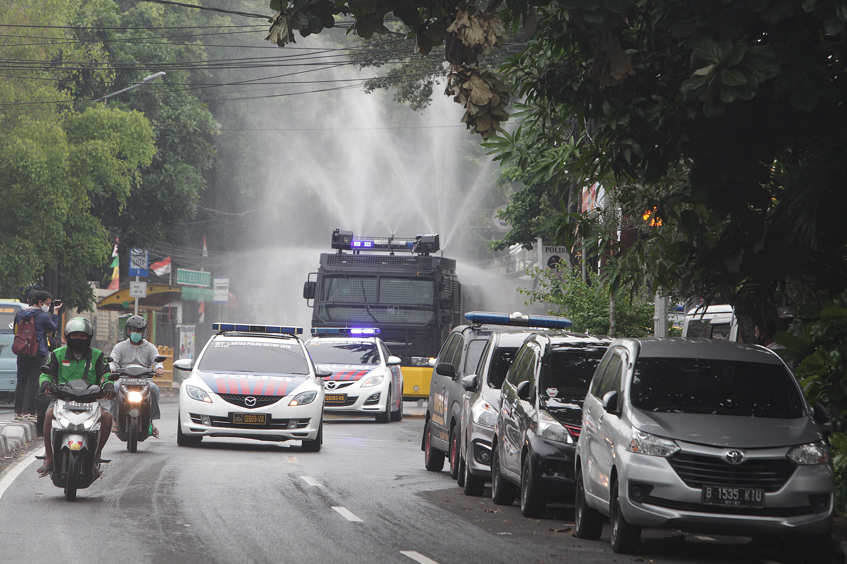 Kendaraan water canon Brimob Polda Metro Jaya menyemprot cairan disinfektan di sepanjang jalan kawasan Petamburan, Jakarta Pusat, Jakarta/