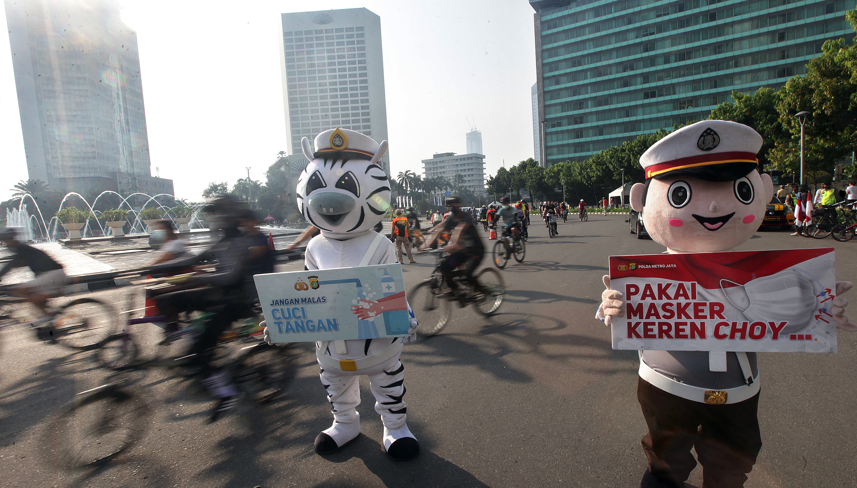 Polisi melakukan kampanye sosialisasi menggunakan masker dan cuci tangan saat hari bebas kendaraan bermotor di kawasan Sudirman, Jakarta.
