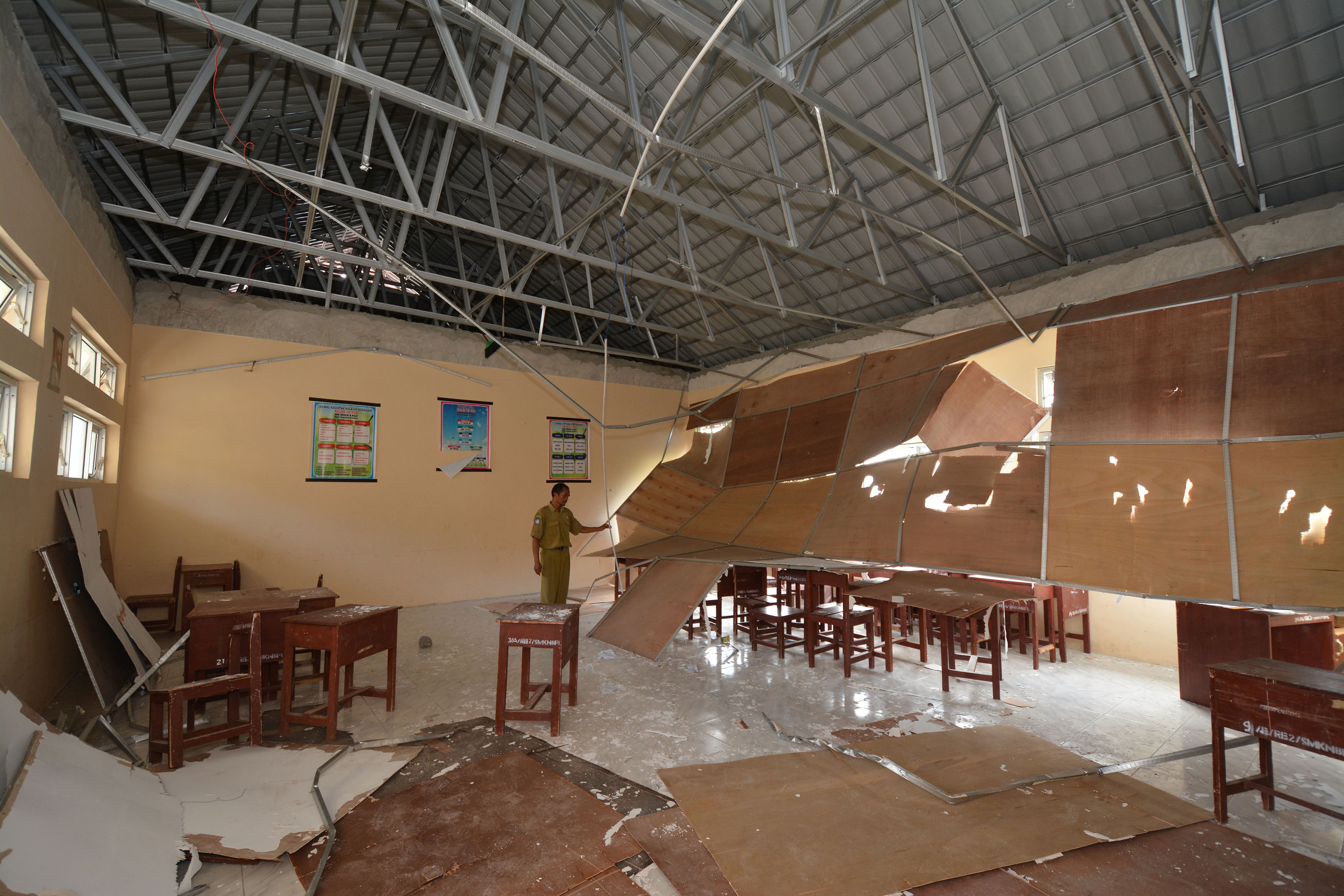 Seorang guru mengamati plafon ruang kelas yang ambruk di SMK Negeri 8 Palu, Sulawesi Tengah.