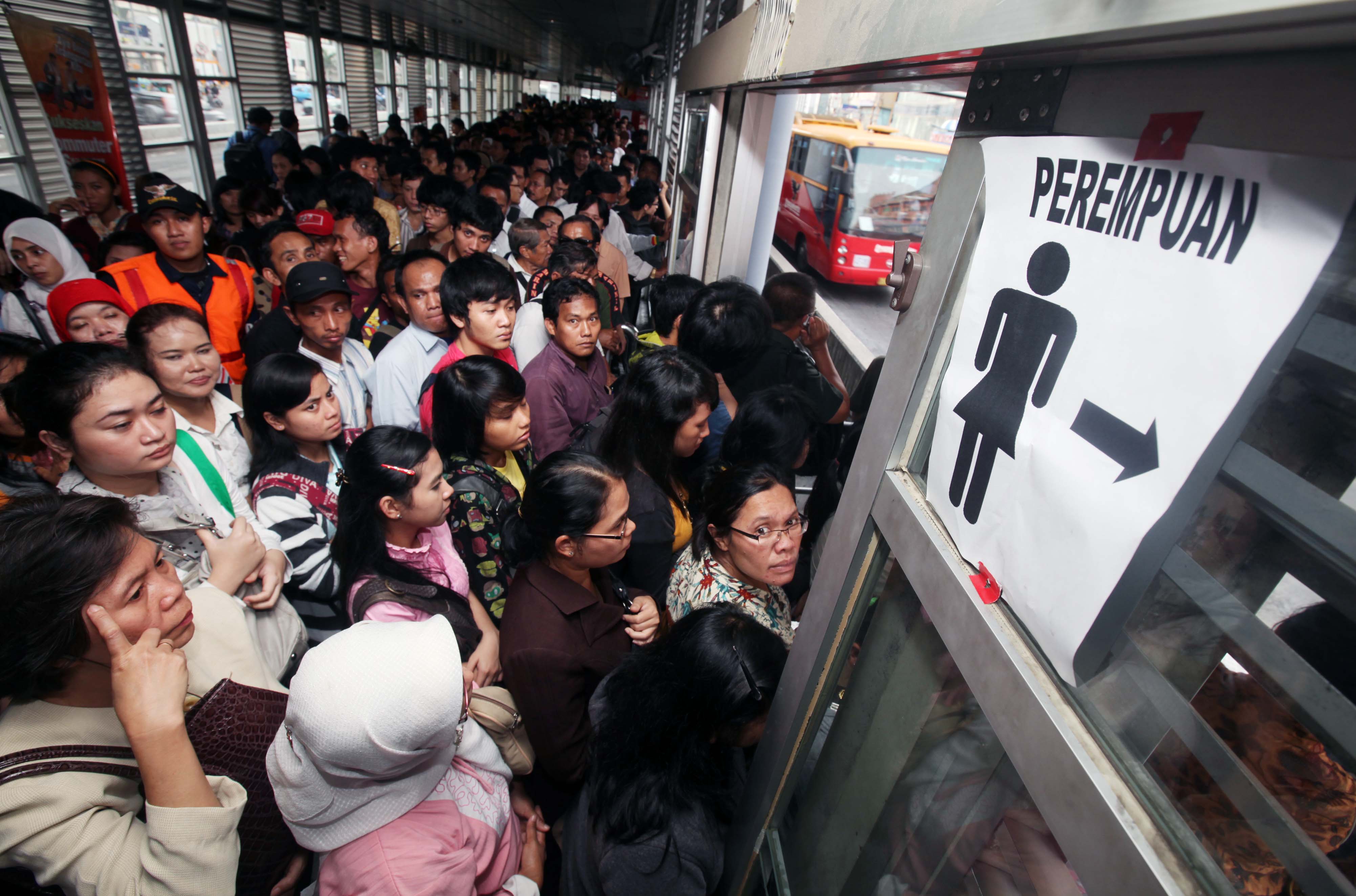 Ilustrasi sejumlah perempuan yang berdesakan menunggu bus Transjakarta.