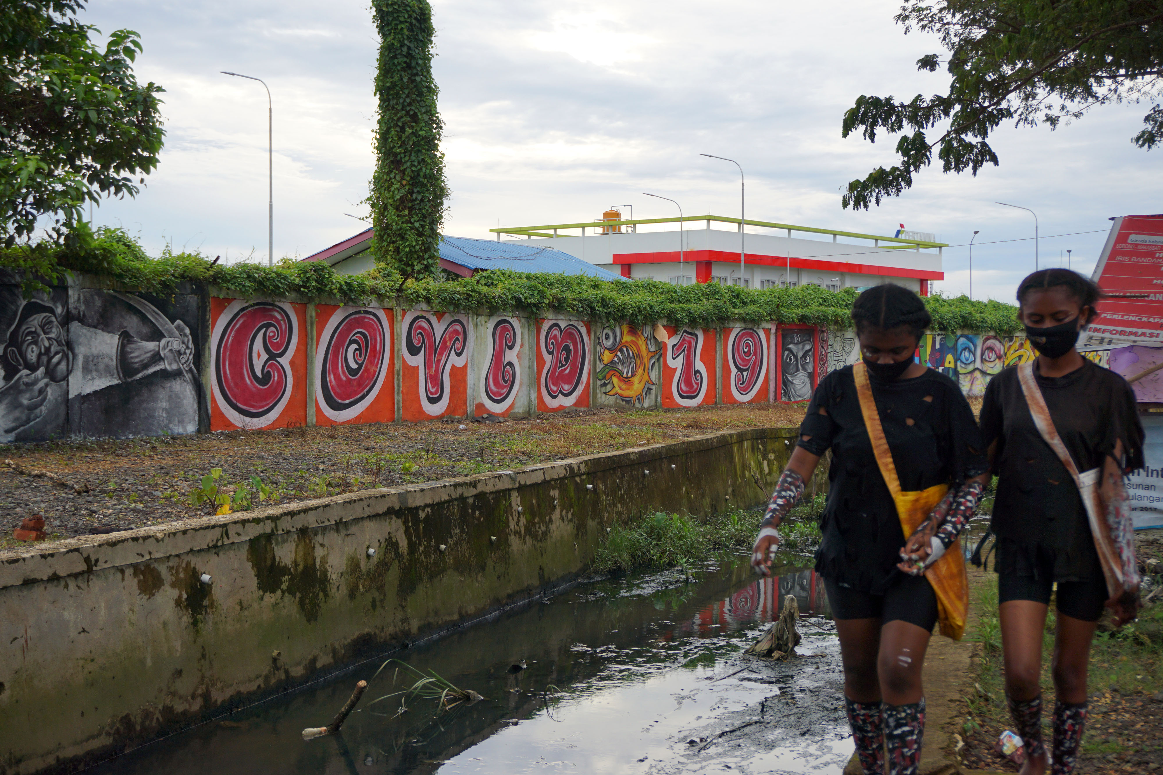 Warga melintas di samping mural peringatan bahaya Covid-19 di Kota Sorong, Papua Barat