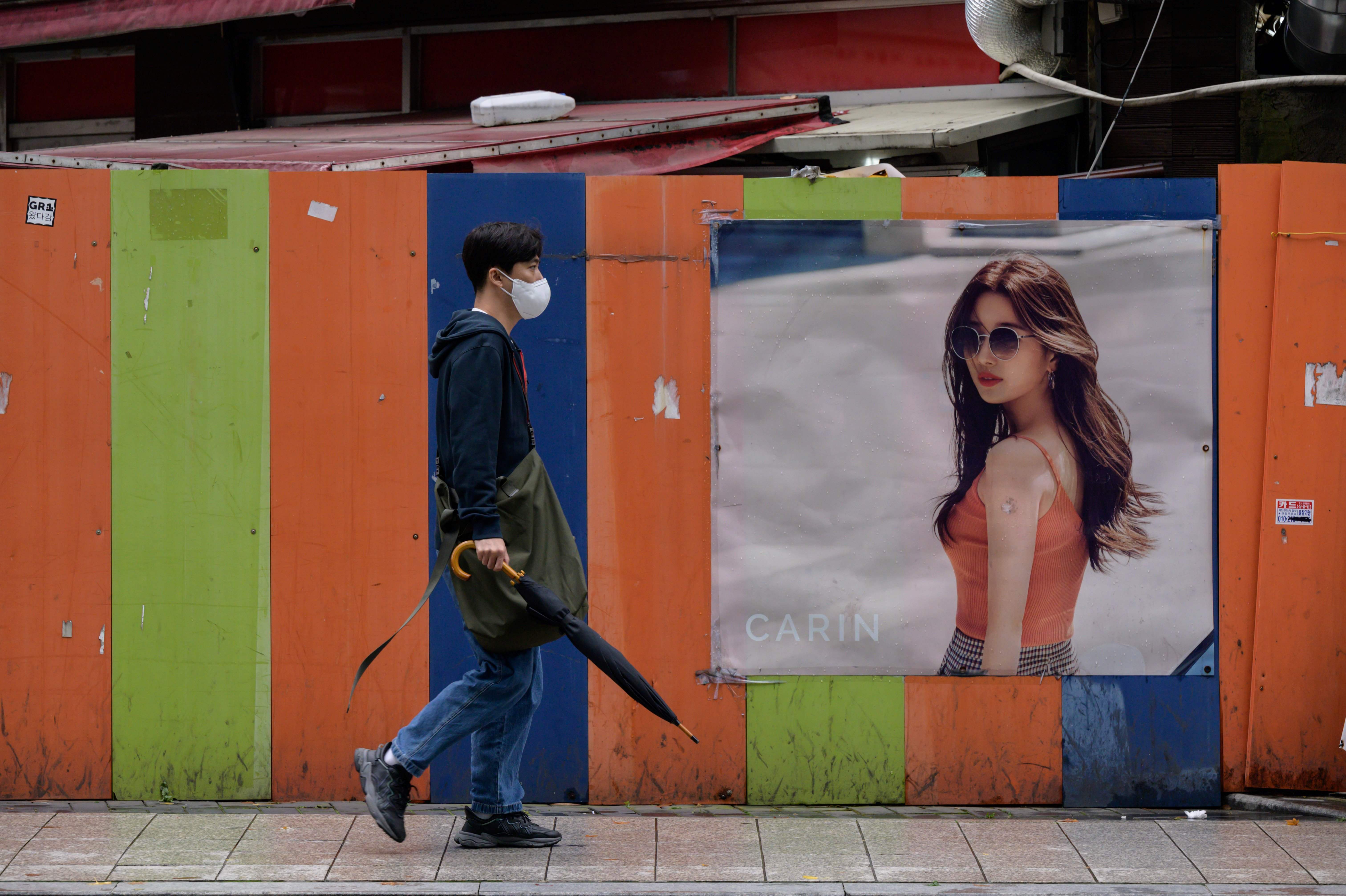 Warga mengenakan masker saat berjalan di Seoul, Korsel.