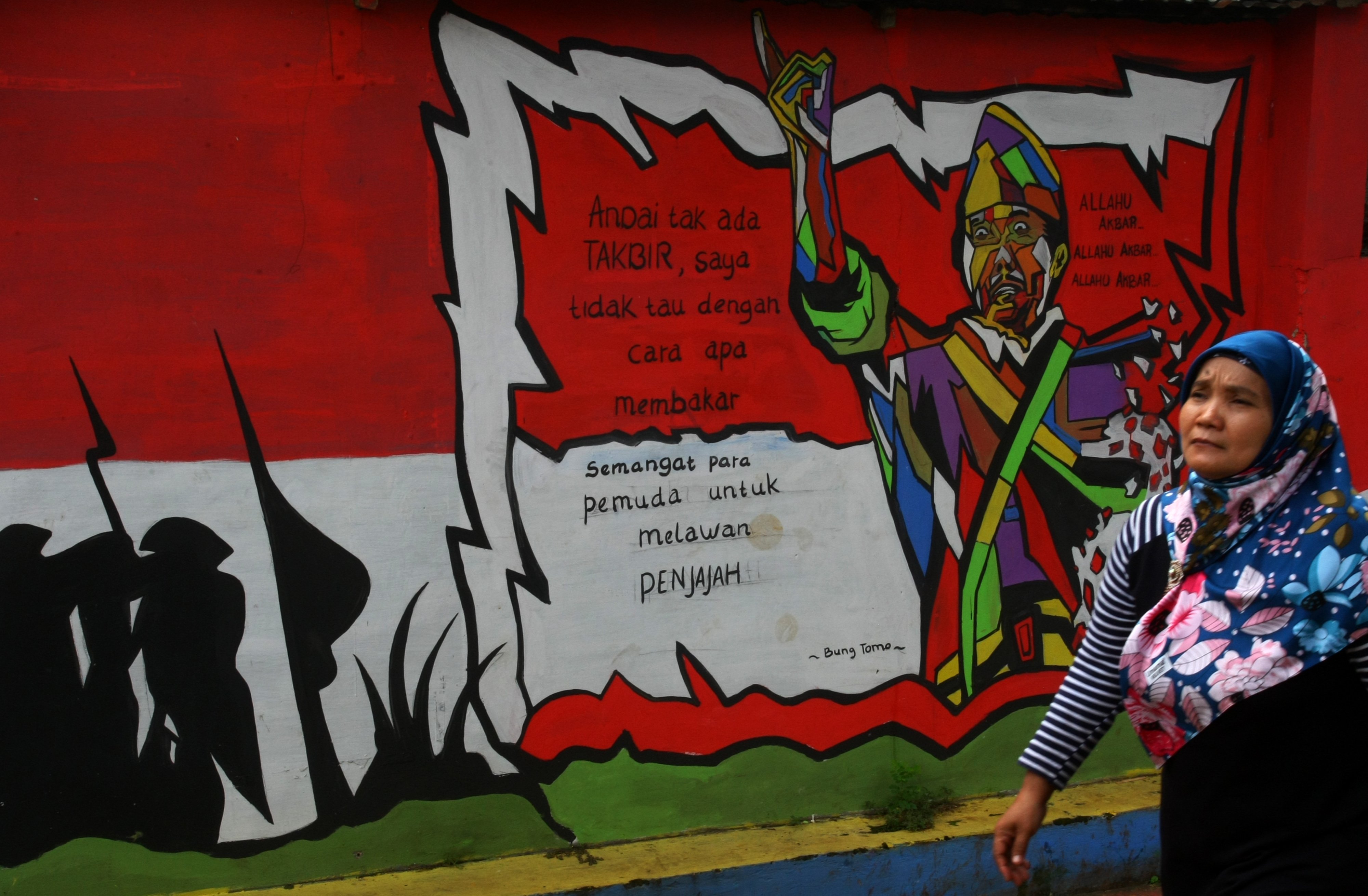Warga melintas di depan mural bergambar pahlawan Bung Tomo, di Ciputat, Tangerang Selatan, Banten.