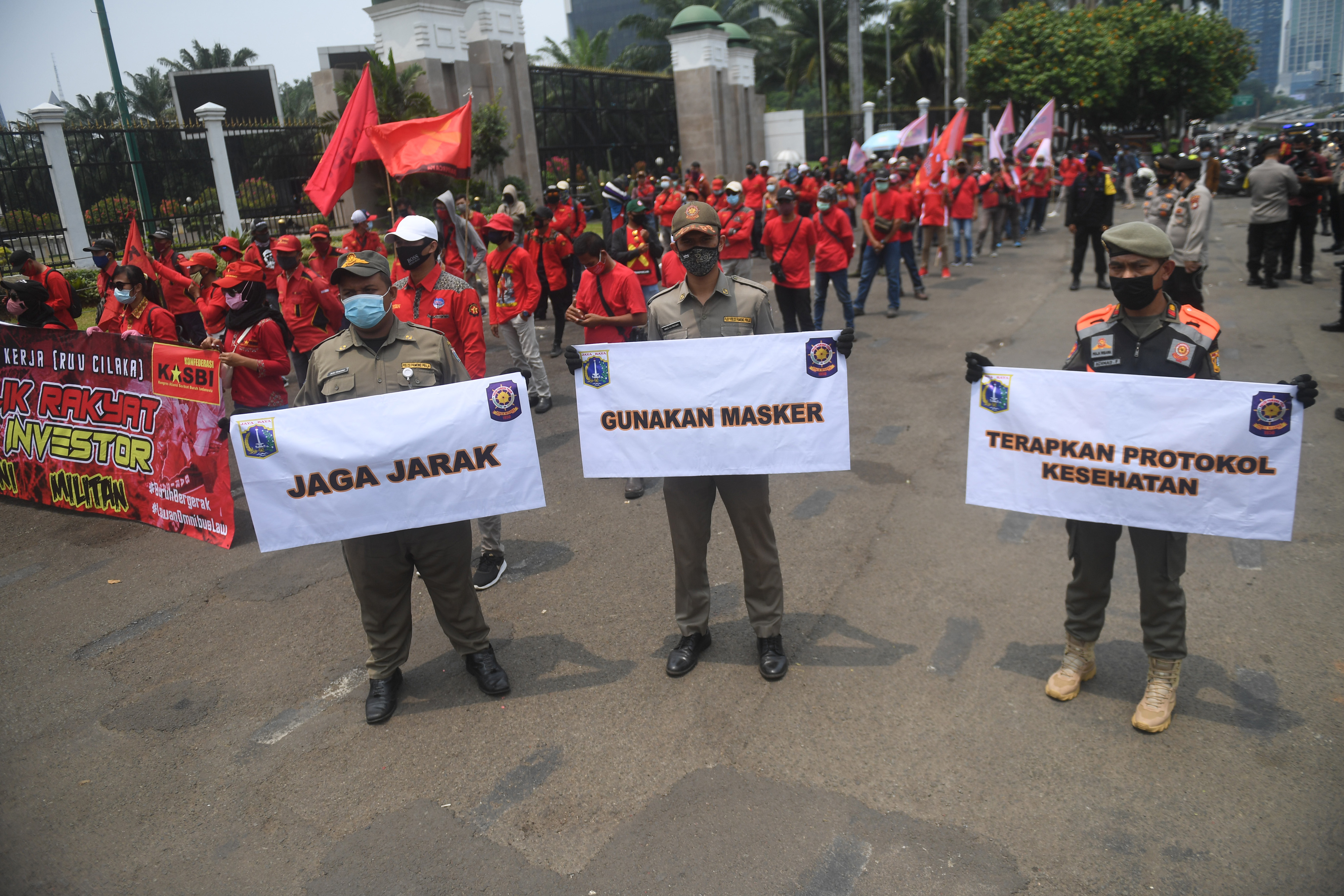 Sejumlah anggota Satpol PP sosialisasi protokol COVID-19 saat aksi unjuk rasa menolak Omnibus Law di depan Kompleks Parlemen, Jakarta.