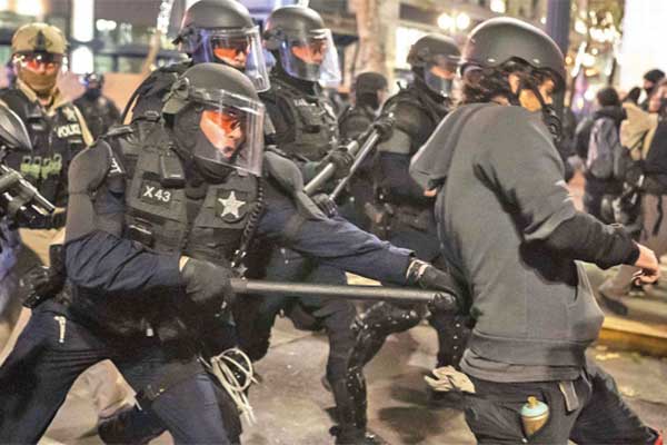 Seorang Polisi Negara bagian Oregon memukul seorang pengunjuk rasa dengan tongkatnya