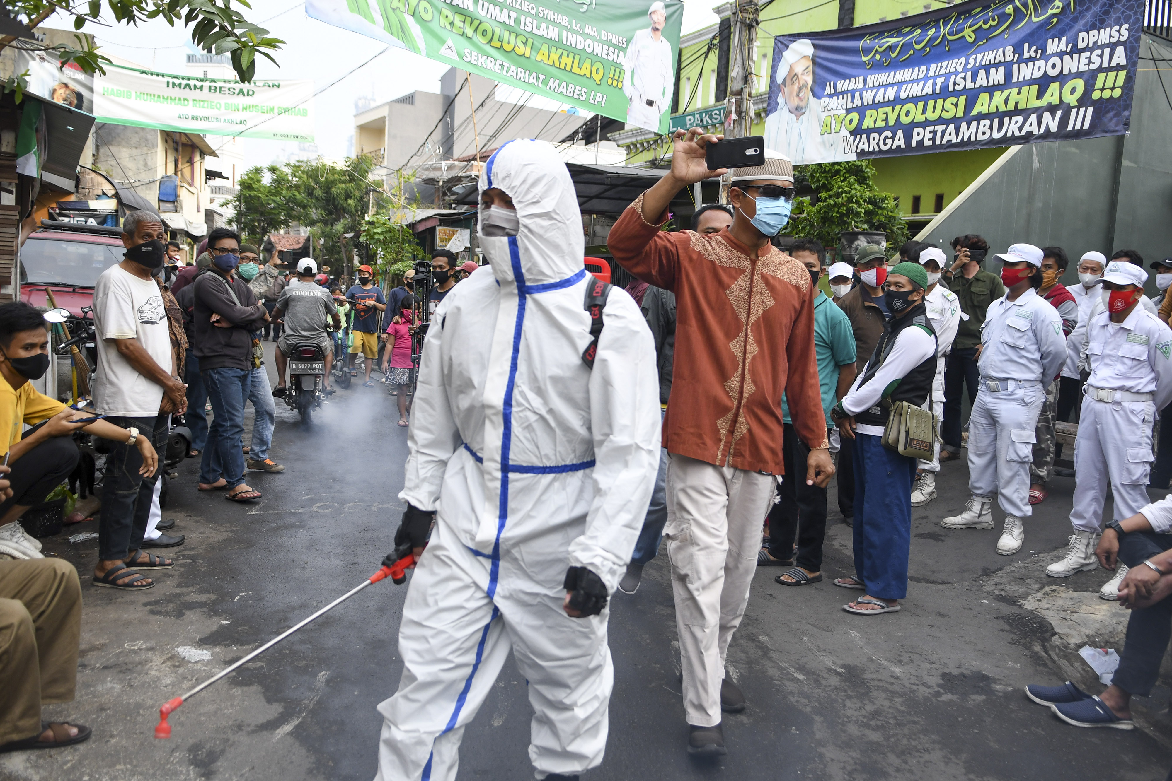 PENYEMPROTAN DISINFEKTAN DI PETAMBURAN: Anggota kepolisian dengan mengenakan hazmat menyemprotkan cairan disinfektan di kawasan Petamburan 