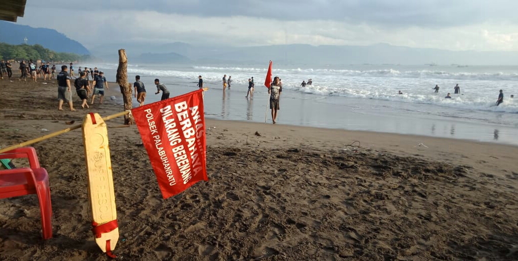 Relawan Badan Penyelamat Wisata Tirta  Kabupaten Sukabumi, Jawa Barat memasang bendera merah tanda bahaya gelombang laut tinggi.